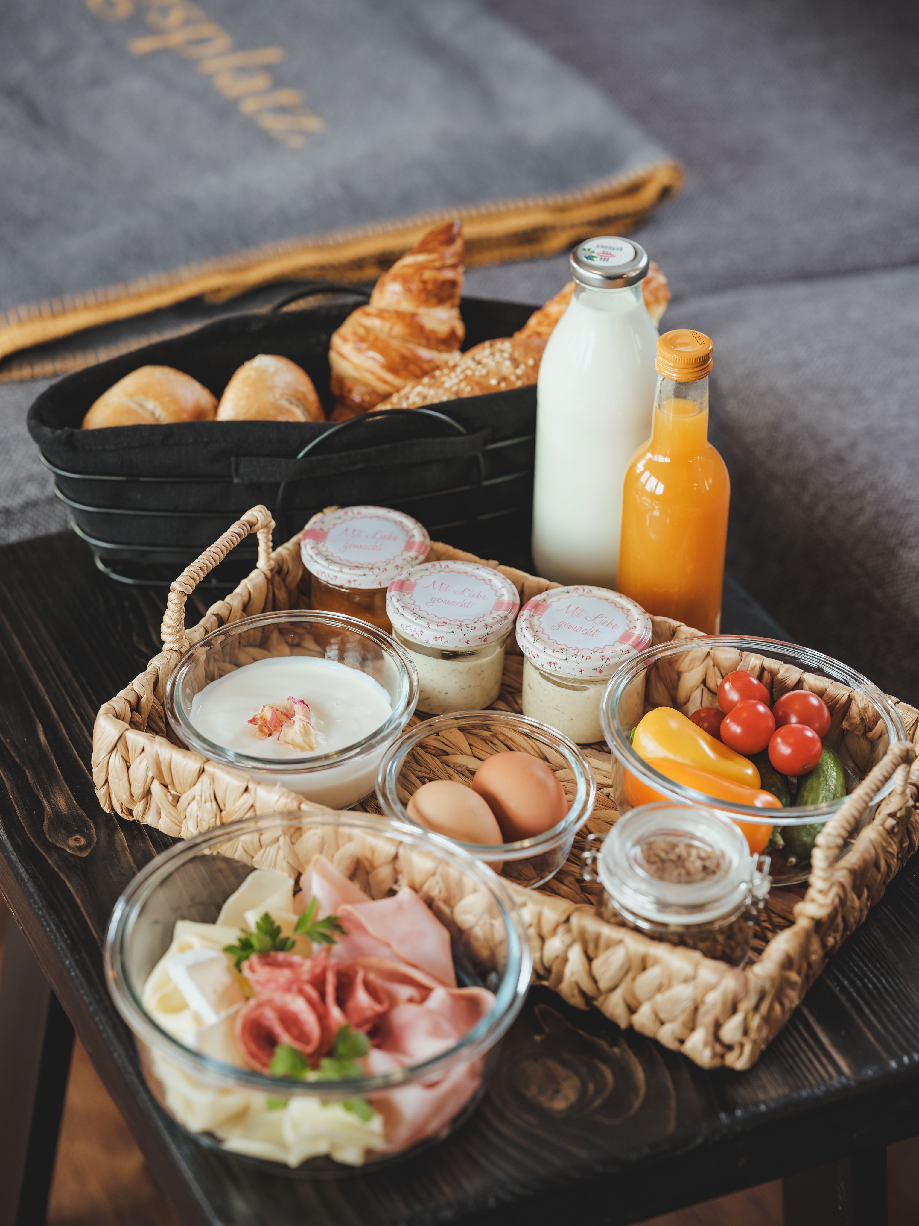 Reggeli tálca zsemlével, croissant, tej, gyümölcslé, joghurt, tojás, felvágottak és zöldségek.