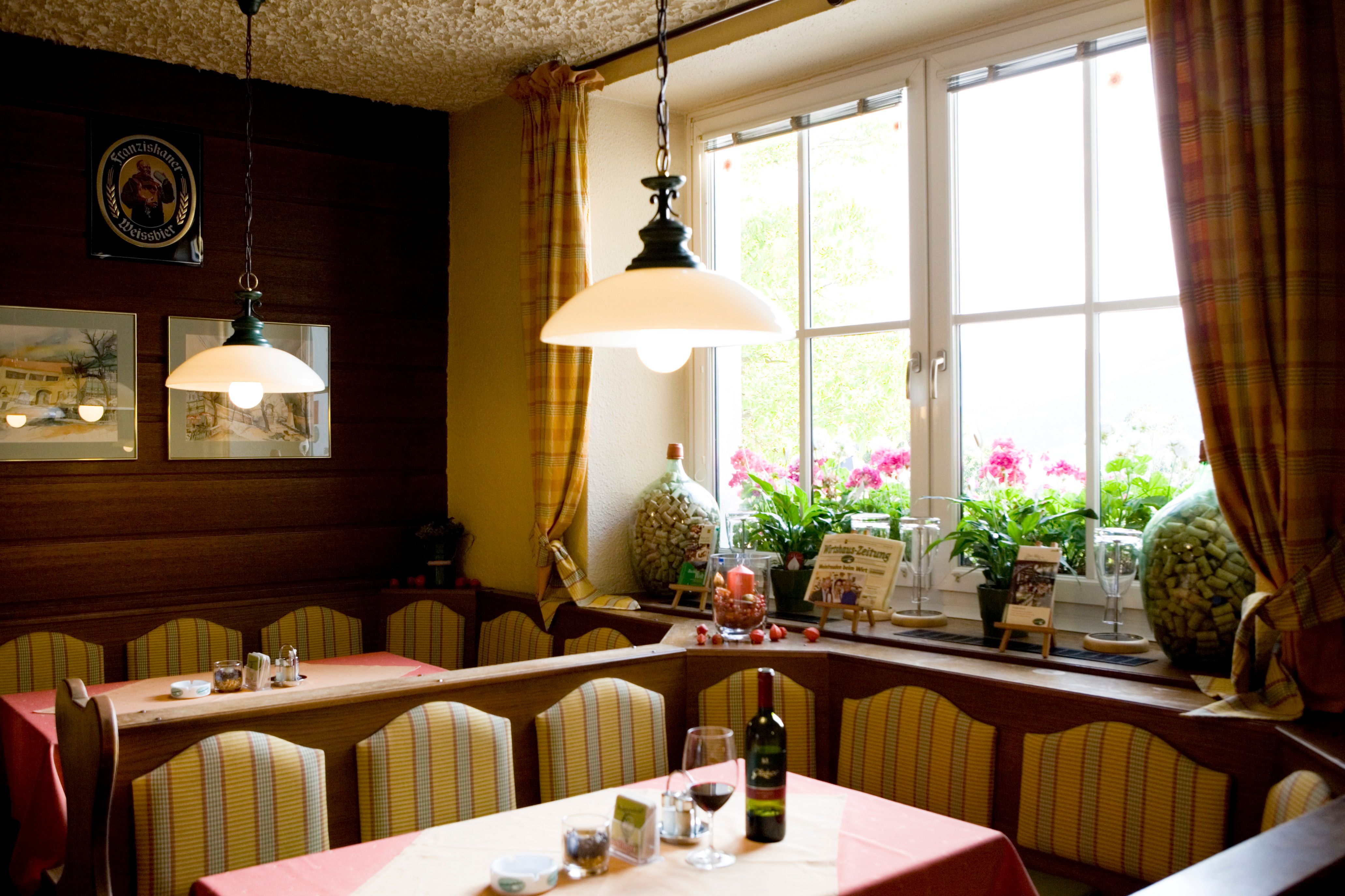 Hangulatos étkező padokkal, asztalokkal, lámpákkal és egy nagy ablakkal, függönyökkel.