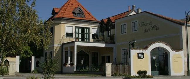 Hagyományos épület sárga homlokzattal és piros cseréptetővel, "Winzerhof zum Wald" felirattal.