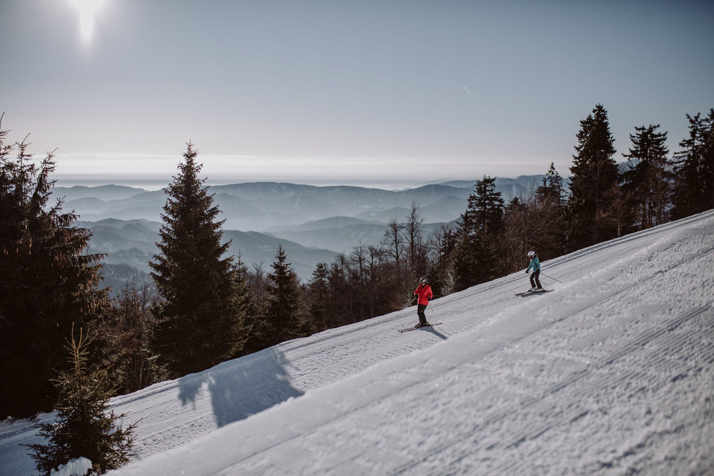 Két síelő az Unterberg síterep egyik pályáján, háttérben a hegyi panoráma.