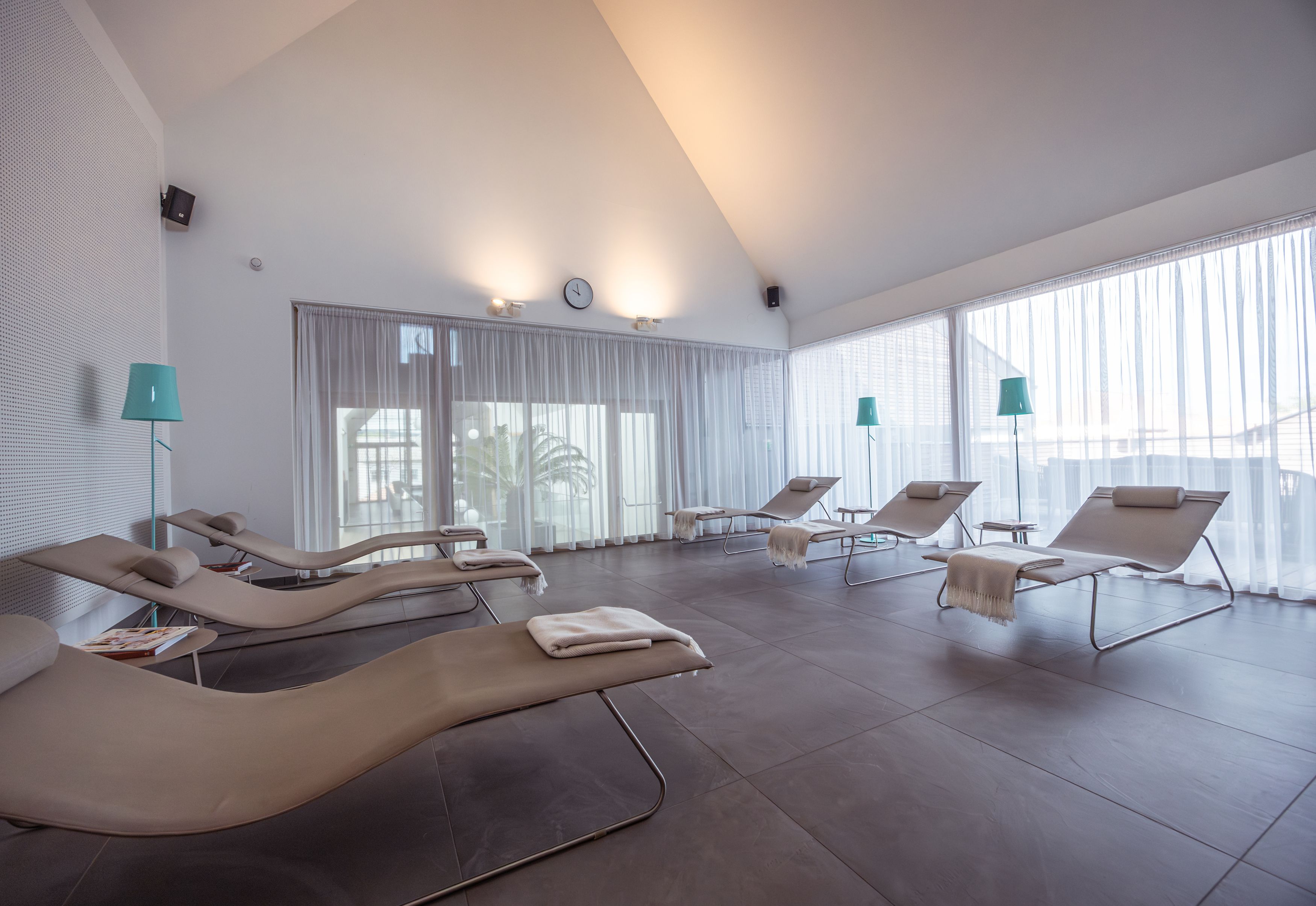 Világos pihenőszoba nyugágyakkal és függönyökkel.