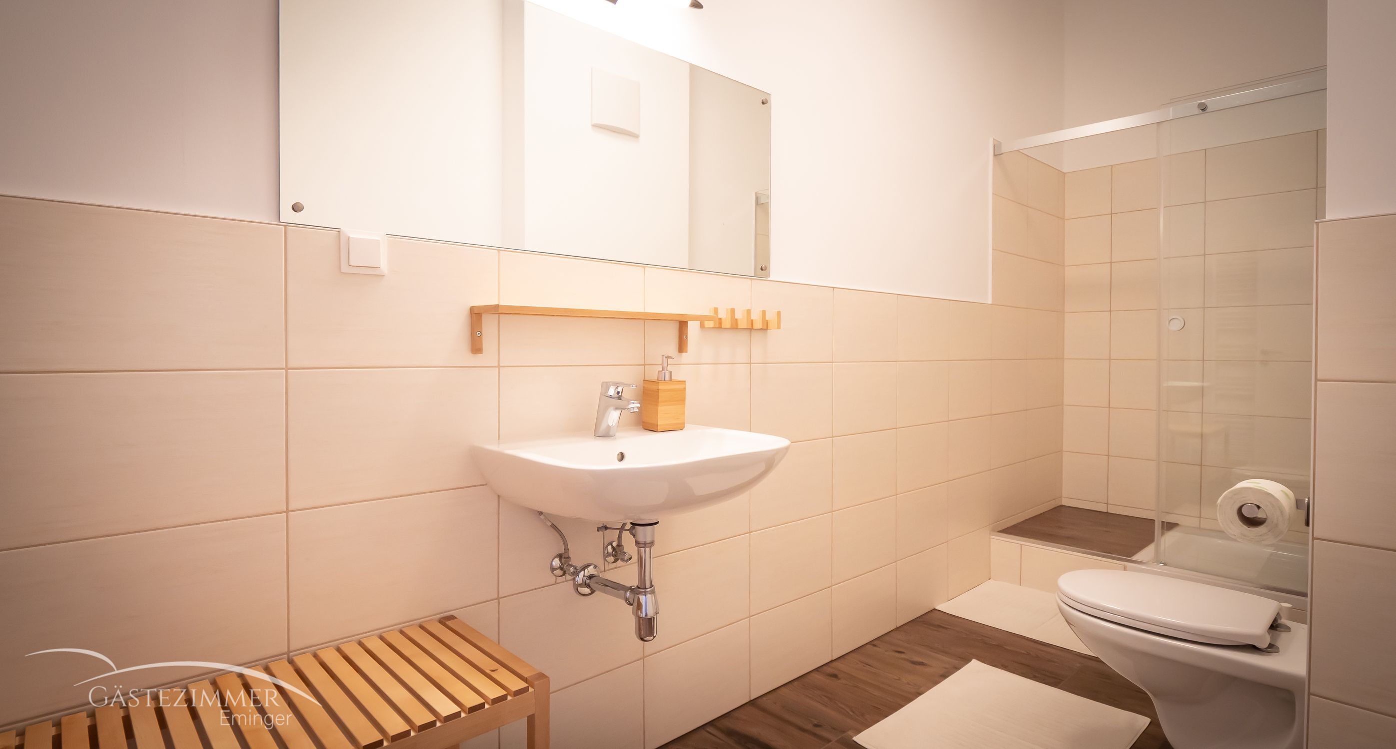 Modern fürdőszoba mosdóval, tükörrel, zuhanyzóval és WC-vel.