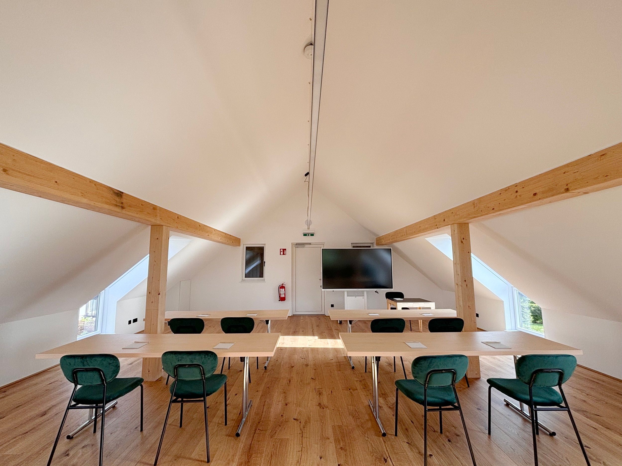 Modern szemináriumi terem fagerendákkal, asztalokkal és székekkel.