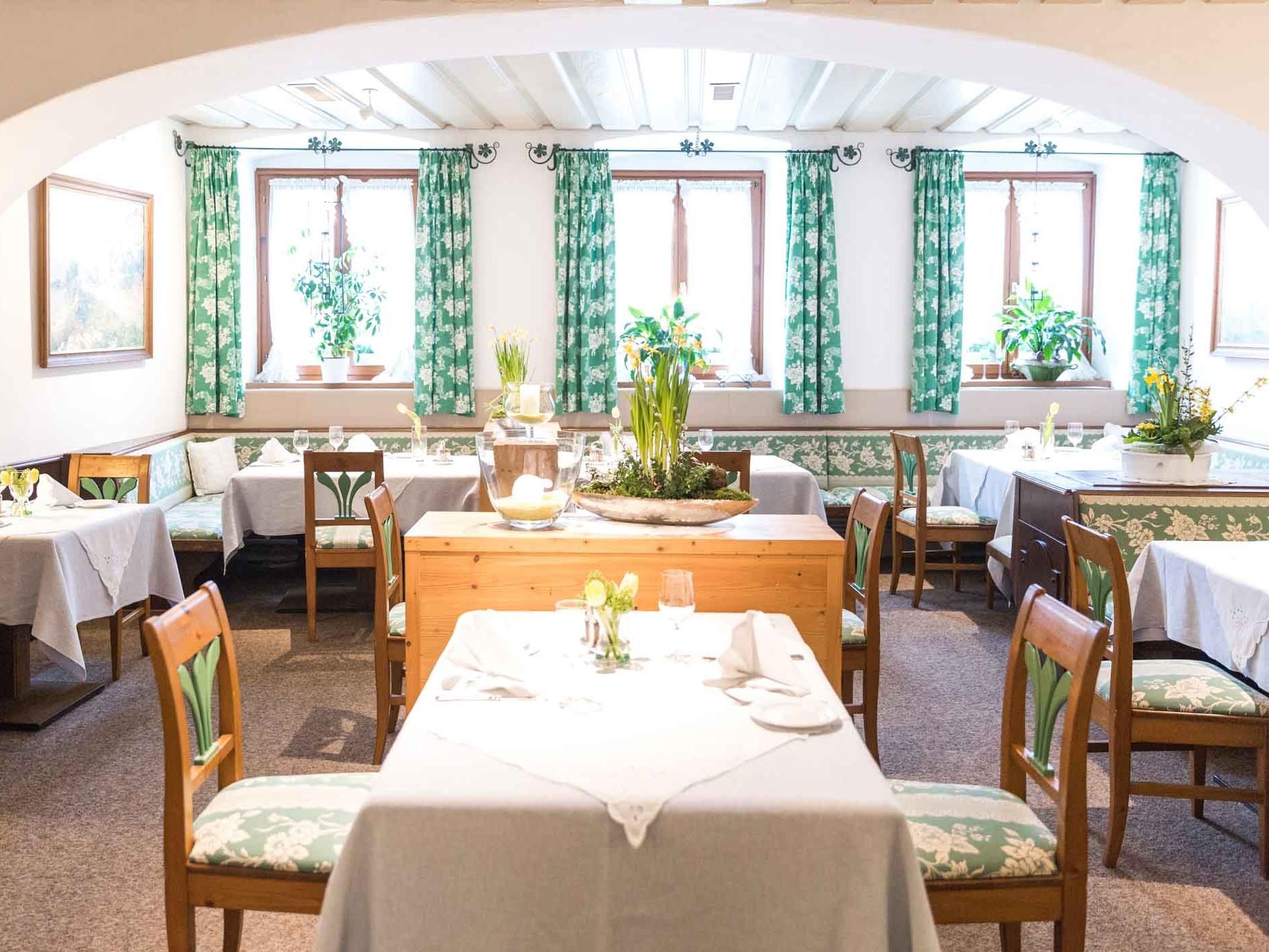 Hangulatos étkező fabútorokkal és zöld függönyökkel.