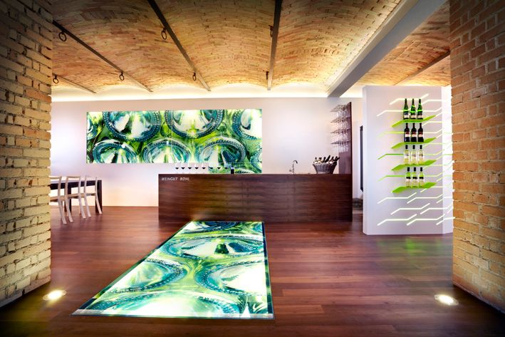 Modern pincészet belső tér, kivilágított padlóval és borosüvegekkel a falon.