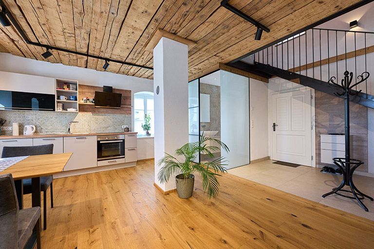 Modern konyha, fa padlóval és mennyezettel, lépcsőházzal és növényekkel.