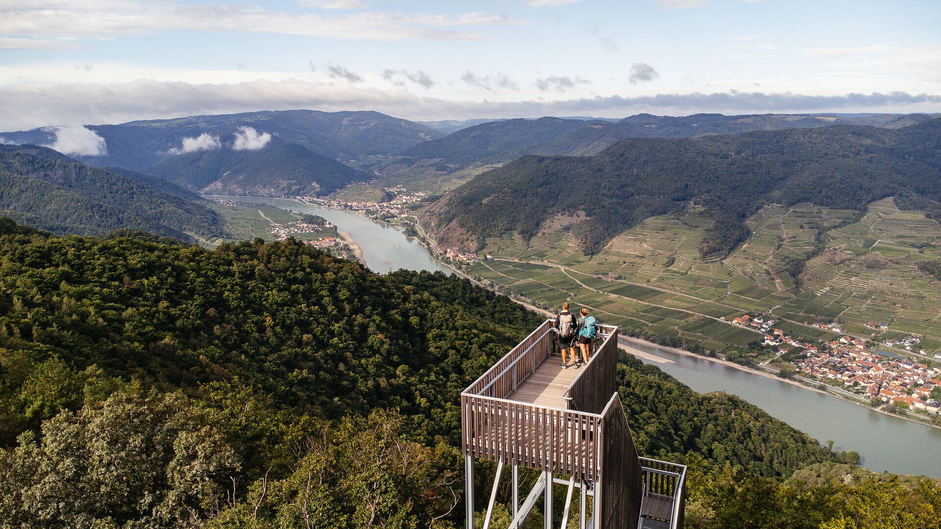 Von der Aussichtsplattform eröffnet sich ein atemberaubender Blick über die sanften Hügel und die glitzernde Donau, die sich durch die malerische Landschaft schlängelt. Die frische Bergluft und das sanfte Rauschen der Bäume laden dazu ein, einen Moment innezuhalten und die Schönheit der Natur zu genießen.