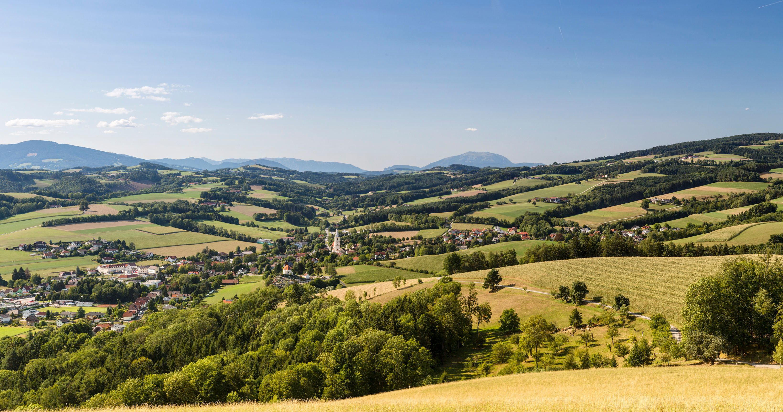 Panorámakép a Bucklige Welt régióból: a völgyben Krumbach település templomtornyával, a háttérben dombok és a Schneeberg hegy.