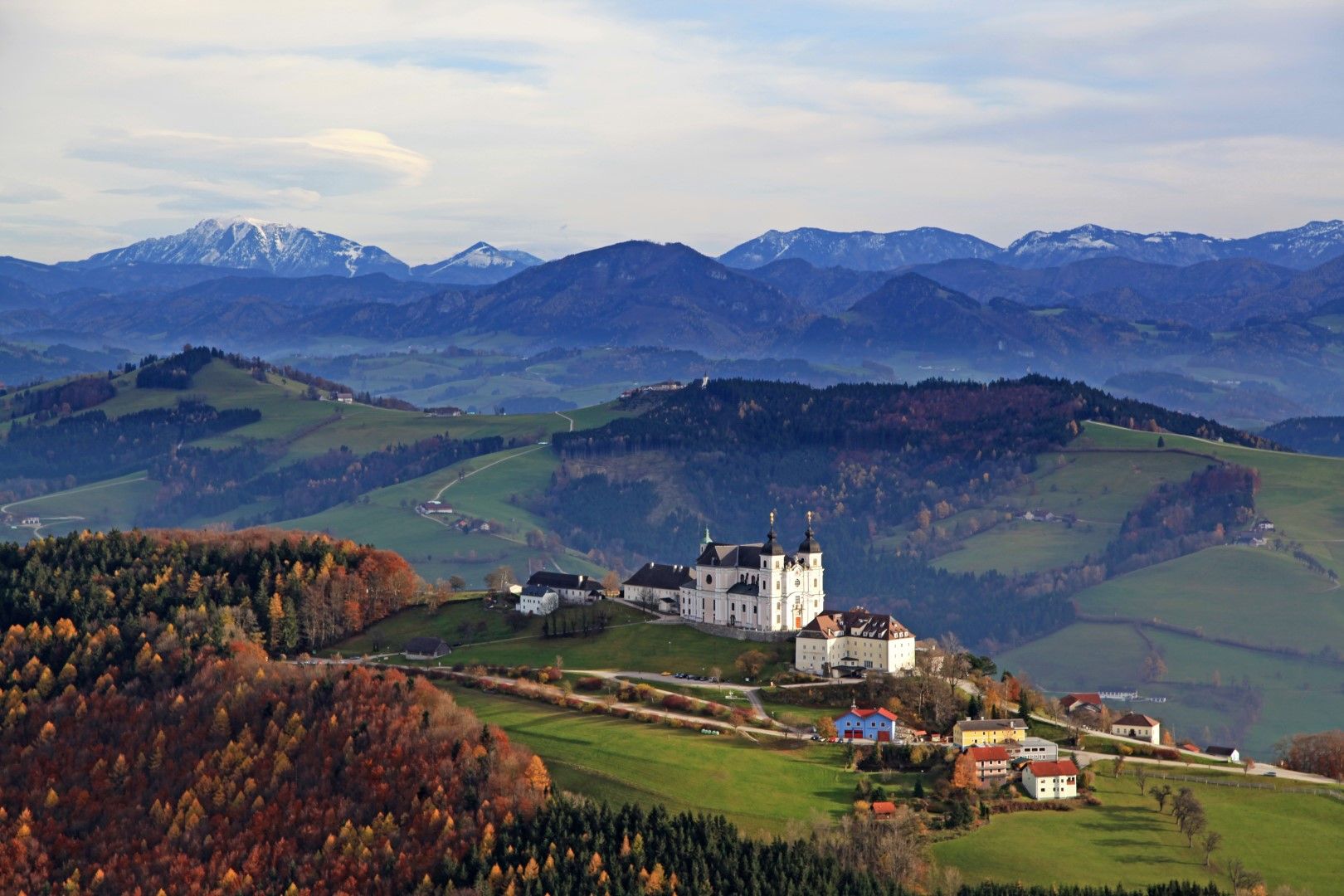 Panoráma a Mostviertel felett, előtérben a Sonntagberg-bazilika, háttérben a hegyek.