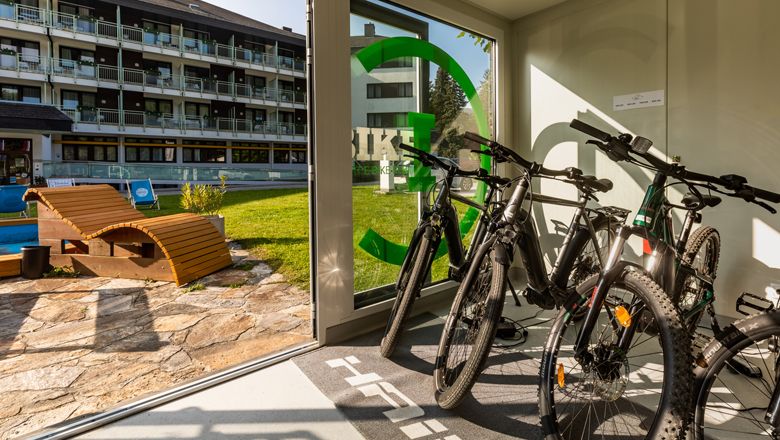 E-kerékpárok egy kölcsönzőben, kilátással a szálloda kertjére.