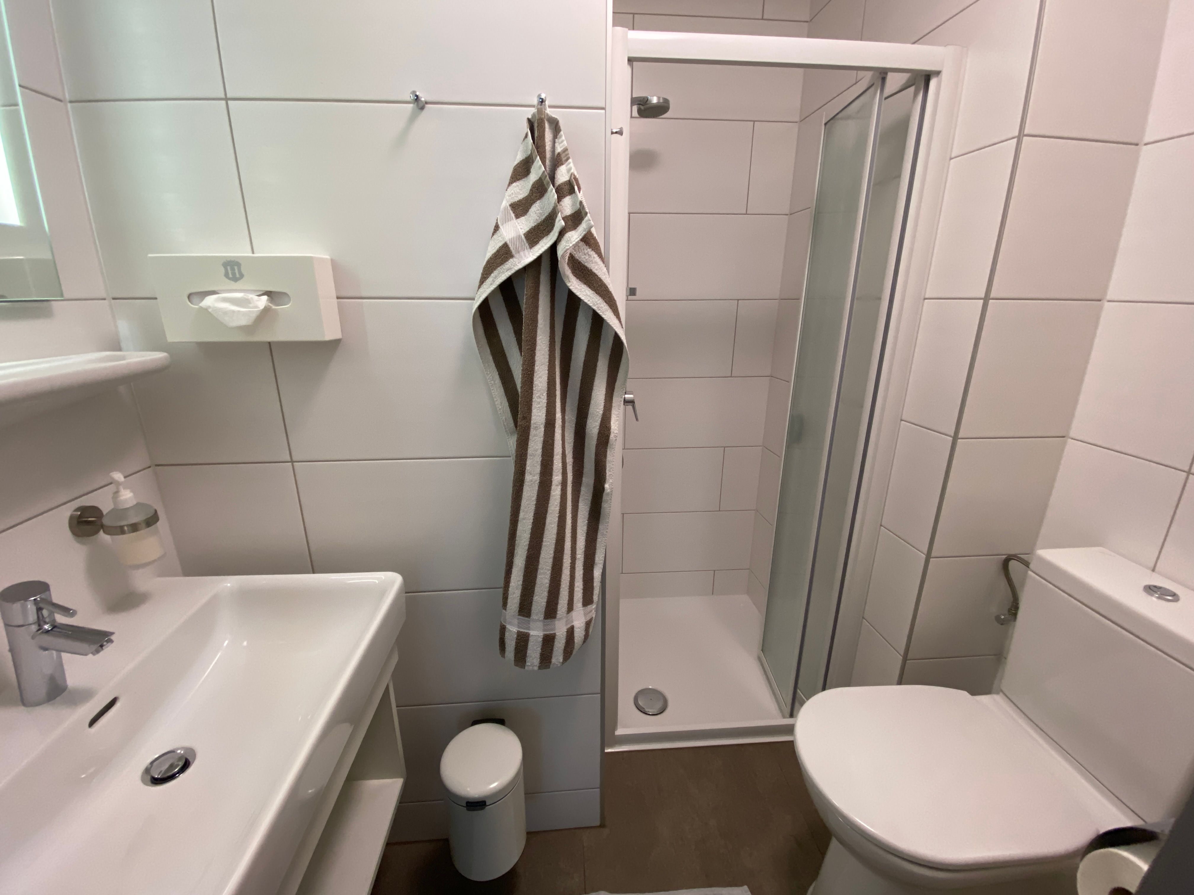 Modern fürdőszoba zuhanyzóval, mosdóval és WC-vel.