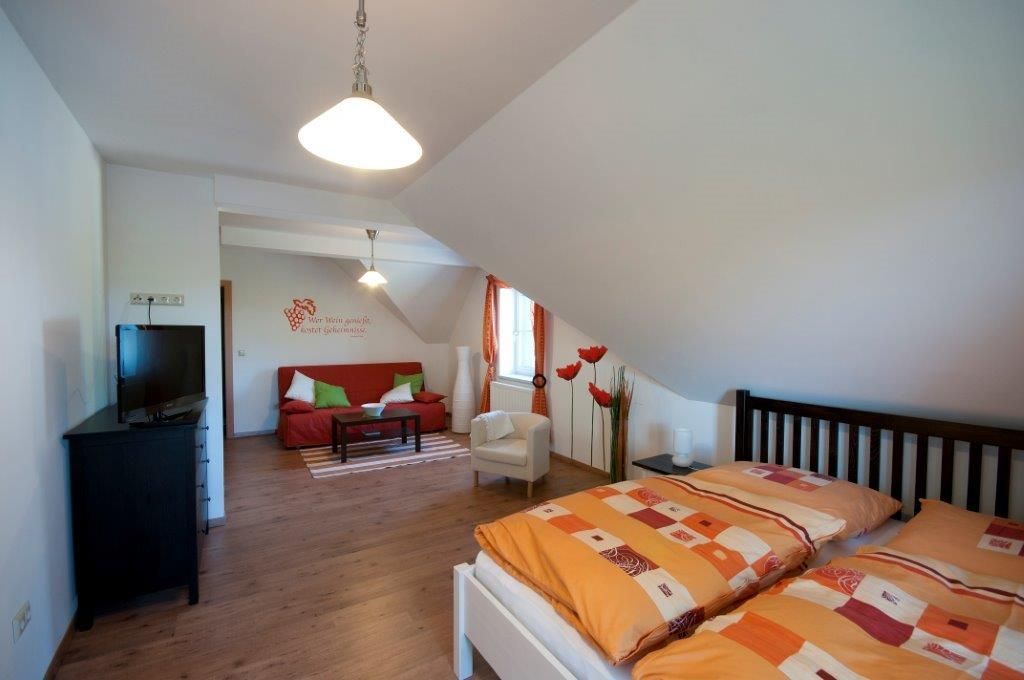 Hangulatos vendégszoba franciaággyal, kanapéval, TV-vel és dekorációs elemekkel.