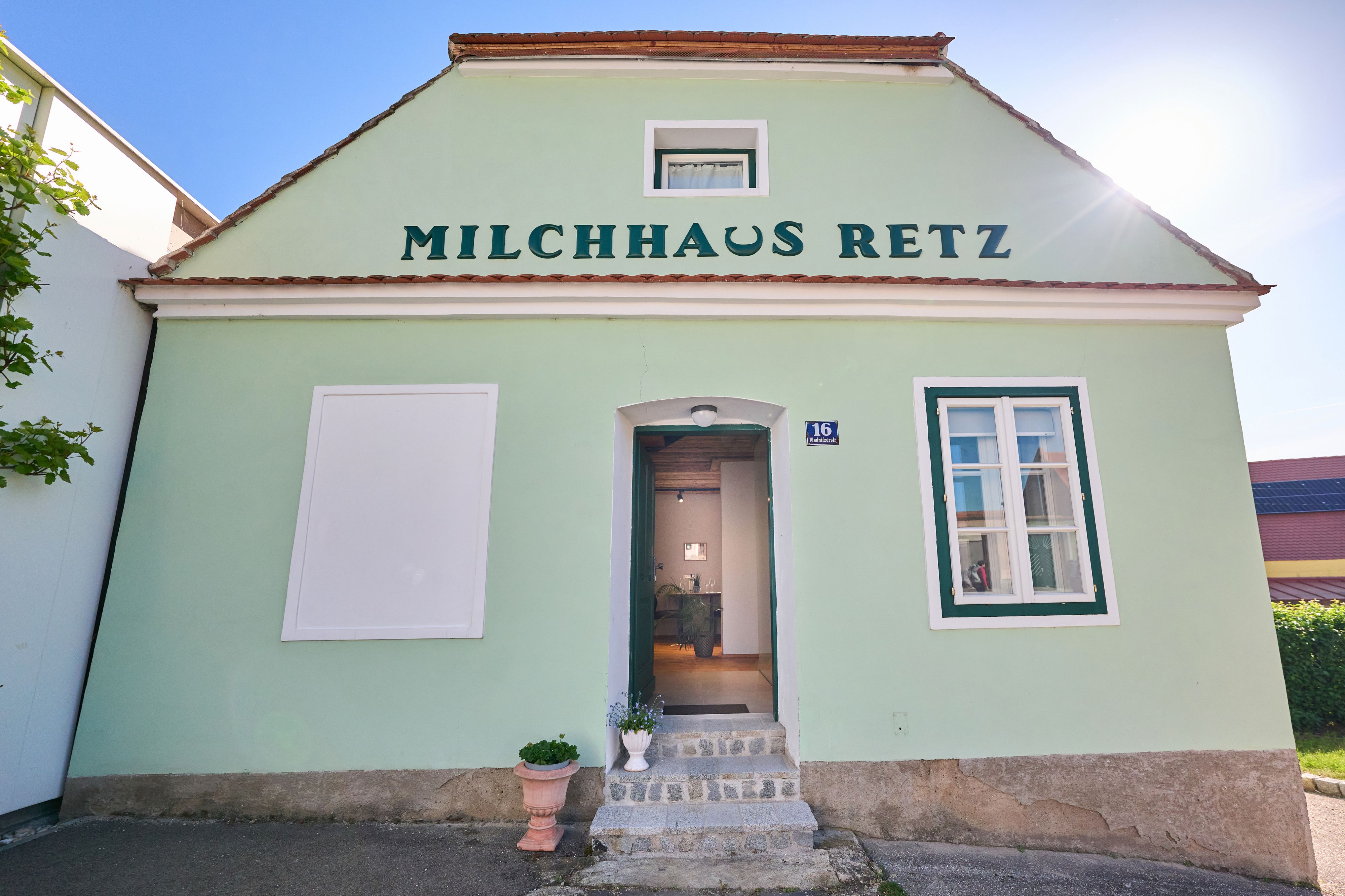 Zöld épület "Milchhaus Retz" felirattal és nyitott ajtóval.
