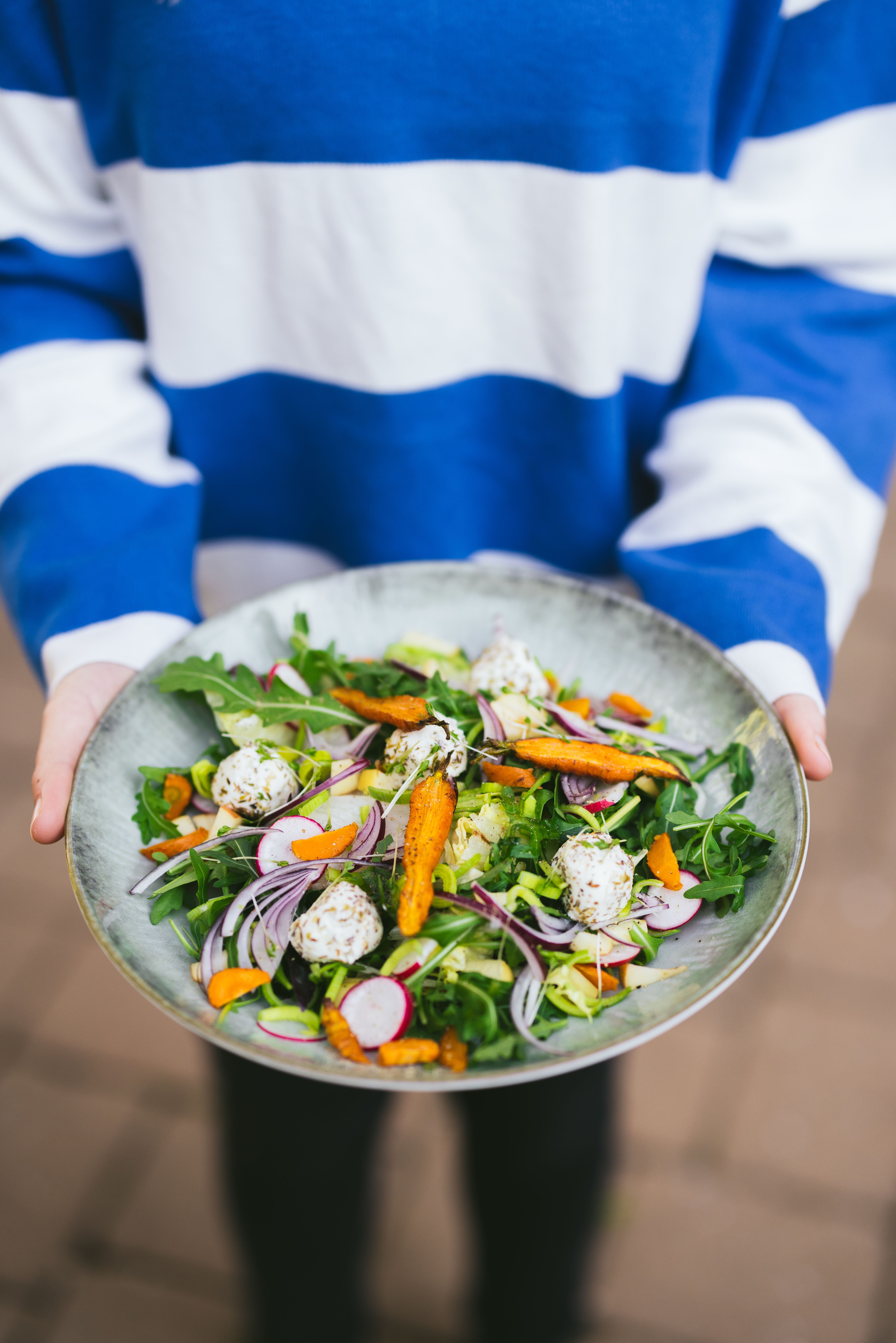 Ein köstlicher Ziegenkäsesalat mit Ofenkarotten wird liebevoll präsentiert, umgeben von frischen, knackigen Blättern. Diese kulinarische Delikatesse lädt dazu ein, die Aromen der Region zu entdecken und die entspannte Atmosphäre eines Heurigen zu genießen.