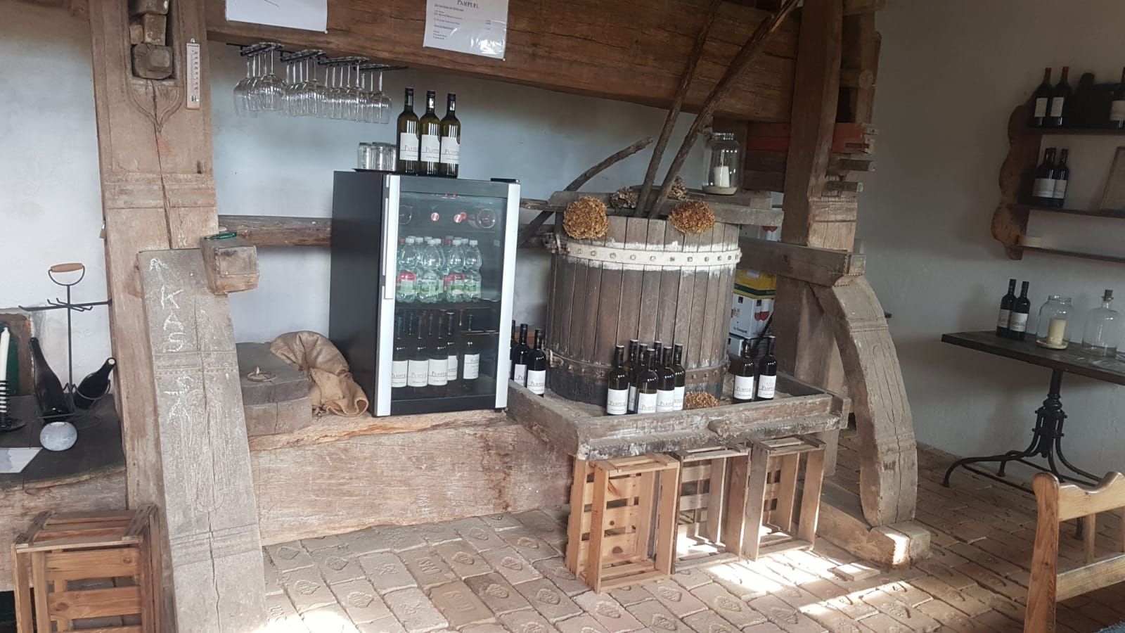 Egy rusztikus borbár belső nézete borosüvegekkel, poharakkal és hűtőszekrénnyel.