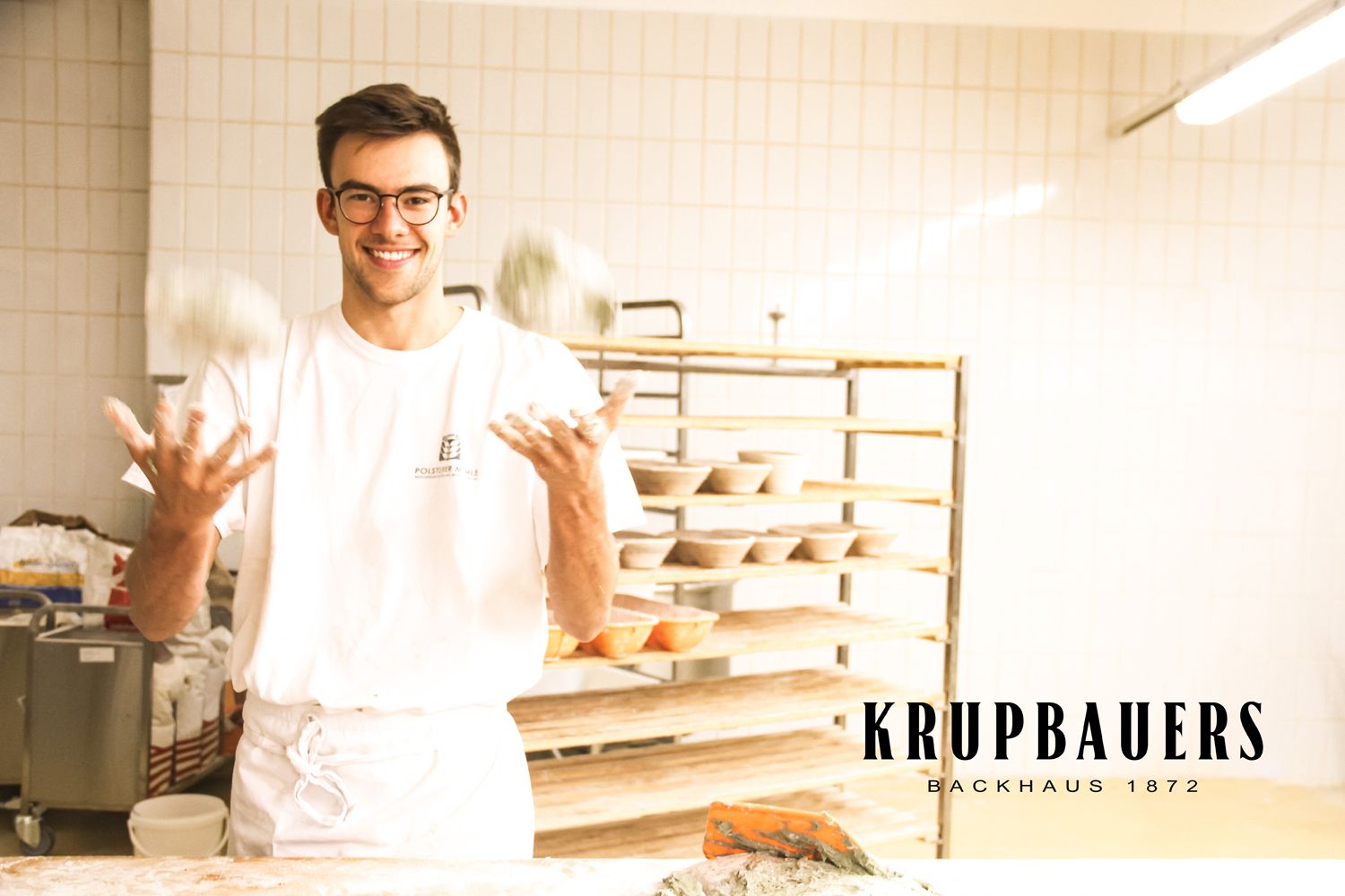 Egy pék zsonglőrködik a tésztagolyókkal egy pékségben.