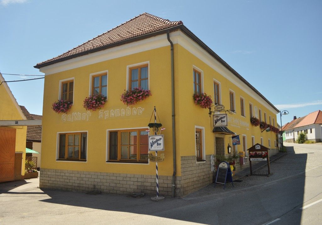 Sárga színű, virágokkal díszített épület "Gasthof Speneder" felirattal.