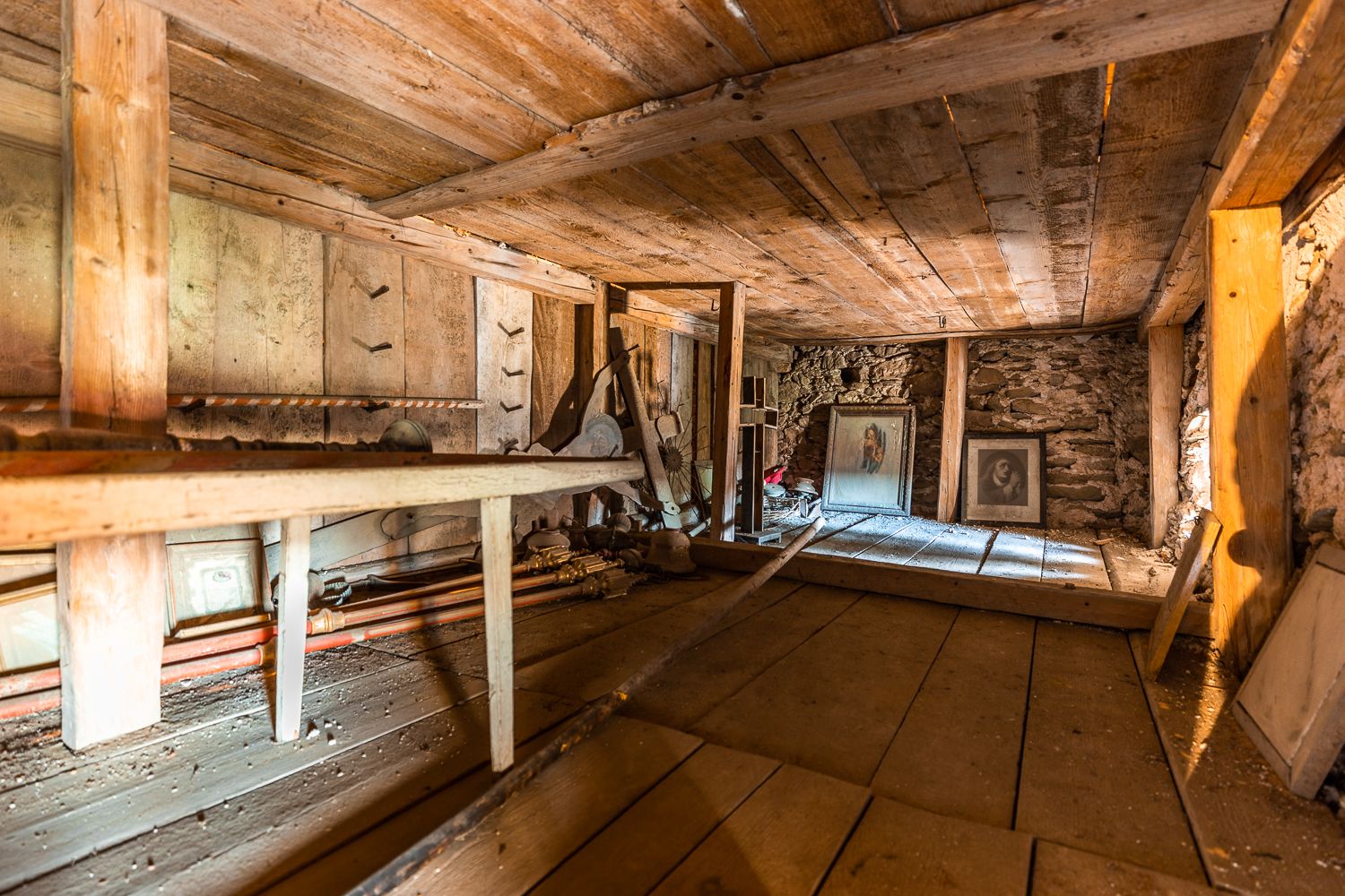Lichtenegg erődtemplomának felső emeletének belső nézete fagerendákkal és régi, poros képekkel.