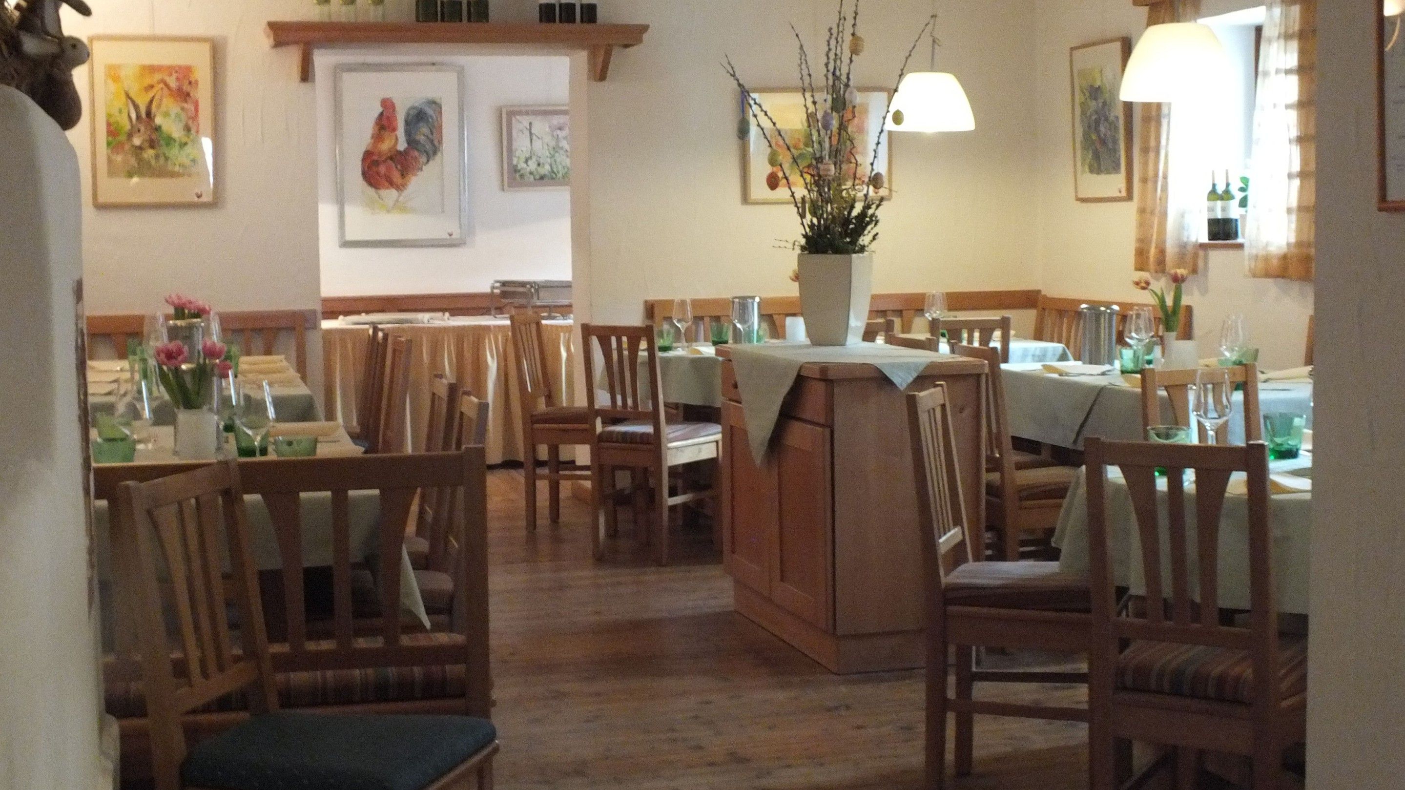 Hangulatos étterem fabútorokkal, terített asztalokkal és virágvázákkal. A falakon állatok képei.