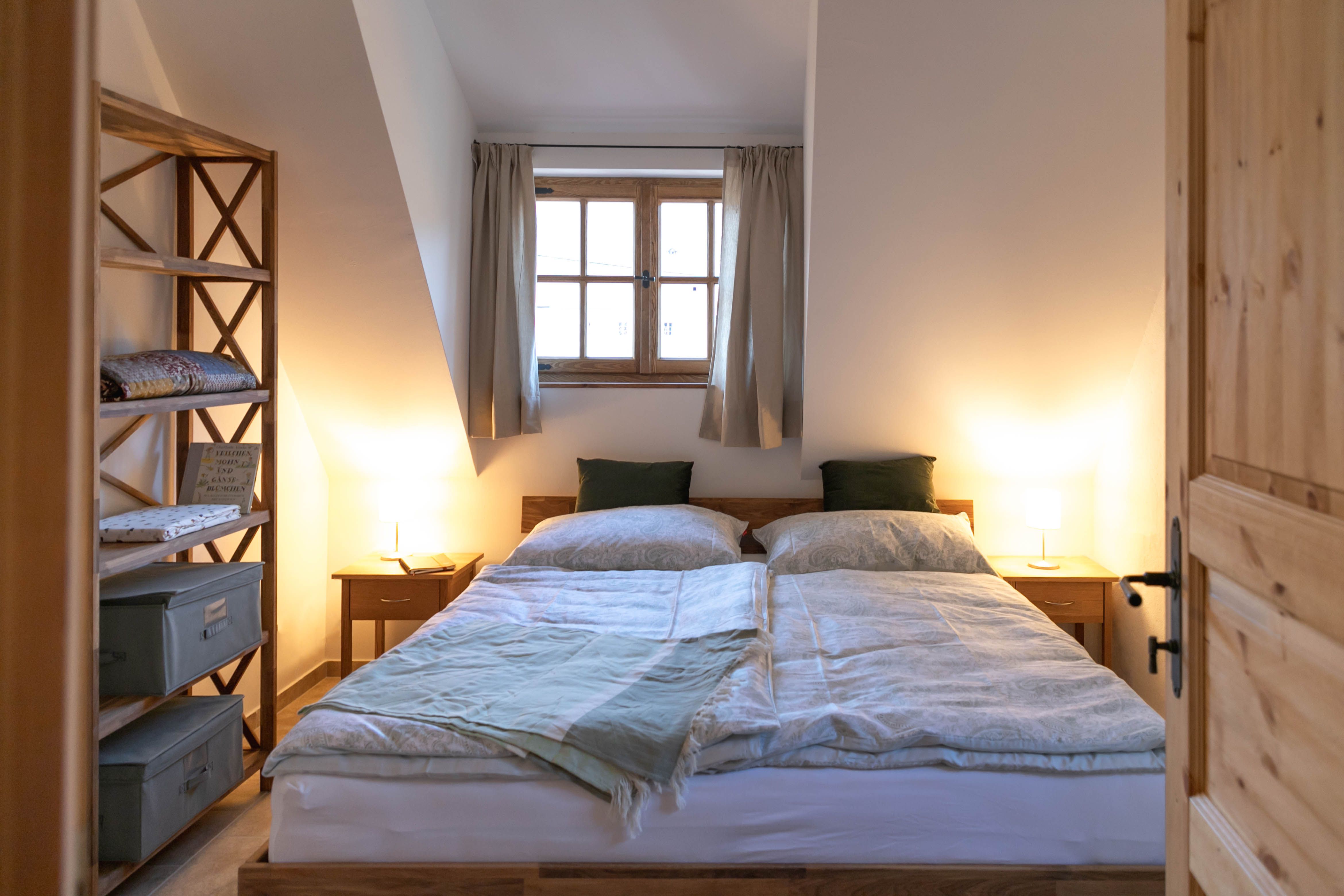 Hangulatos hálószoba franciaággyal, fabútorokkal és függönyös ablakkal.