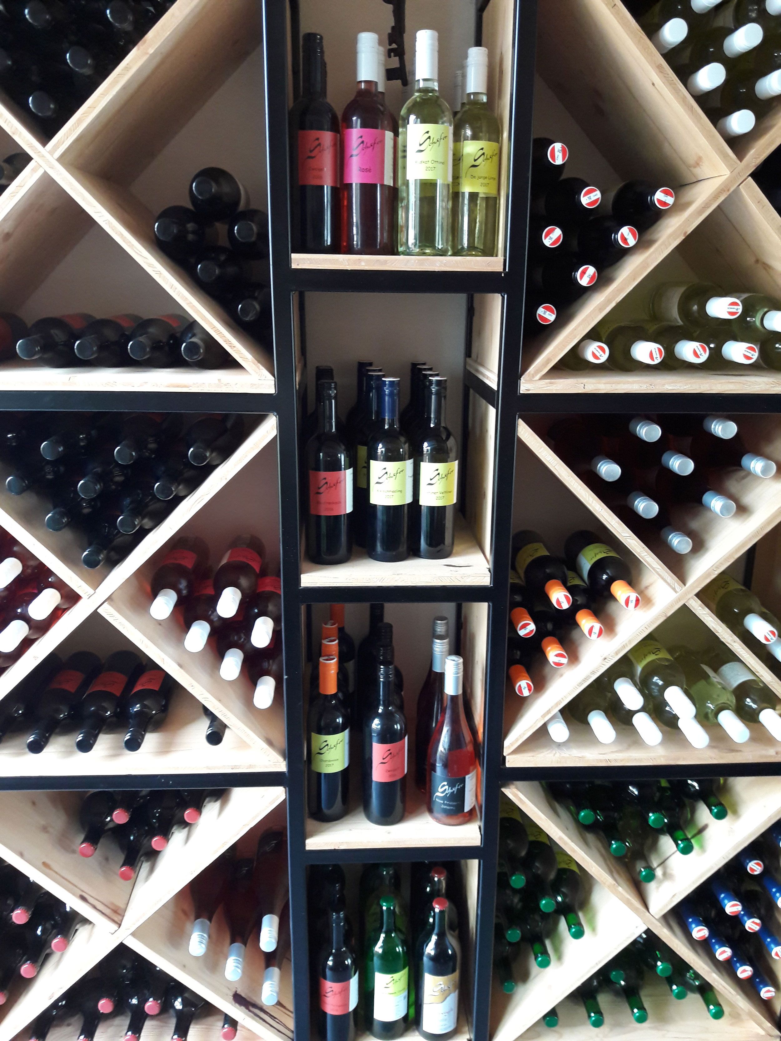 Borosüvegek egy fapolcra helyezett, átlós polcokon.