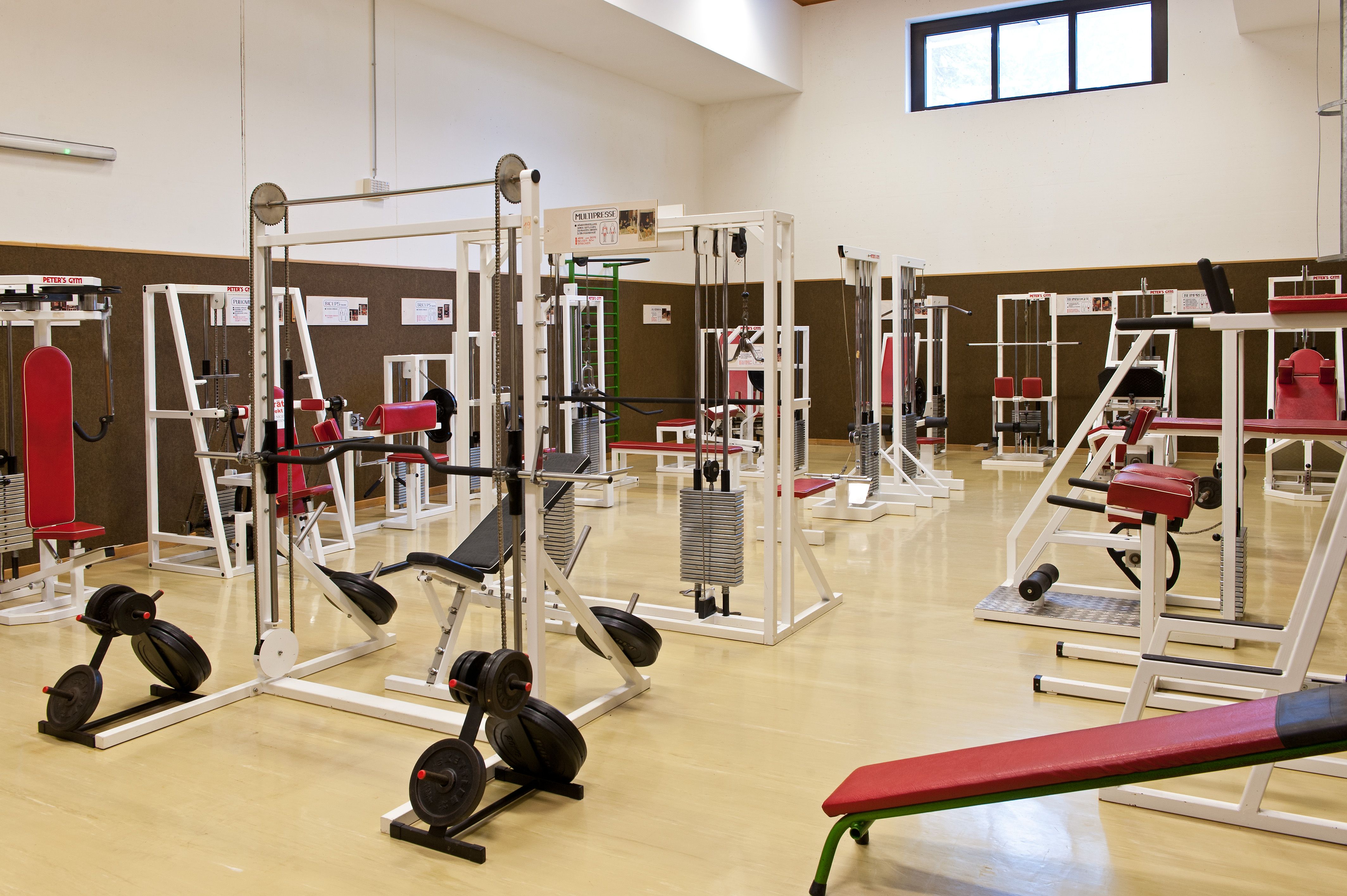 Fitneszterem különböző edzőgépekkel és piros párnákkal.