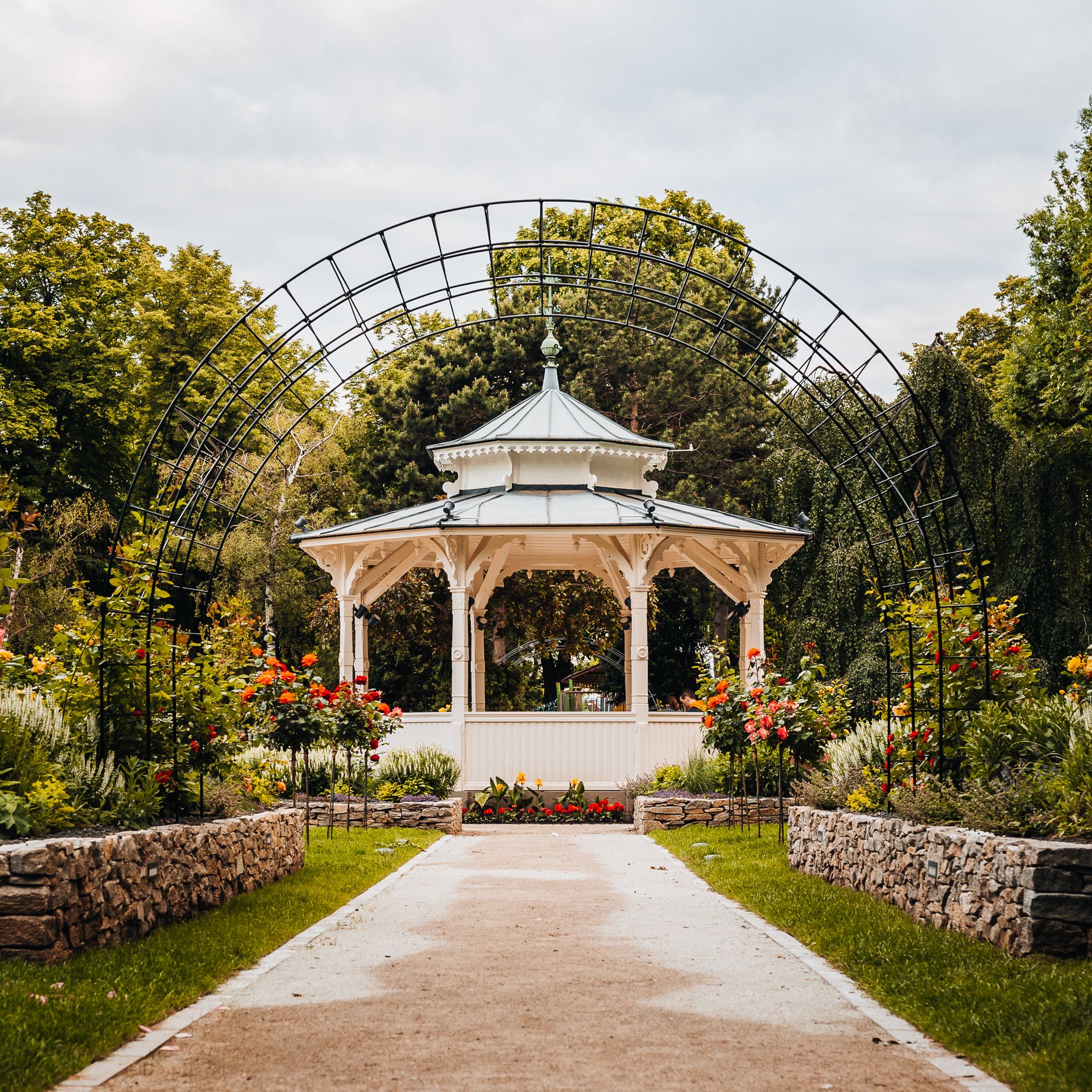 Zöld városi park romantikus pavilonnal, rózsakerttel és rácsos boltívvel