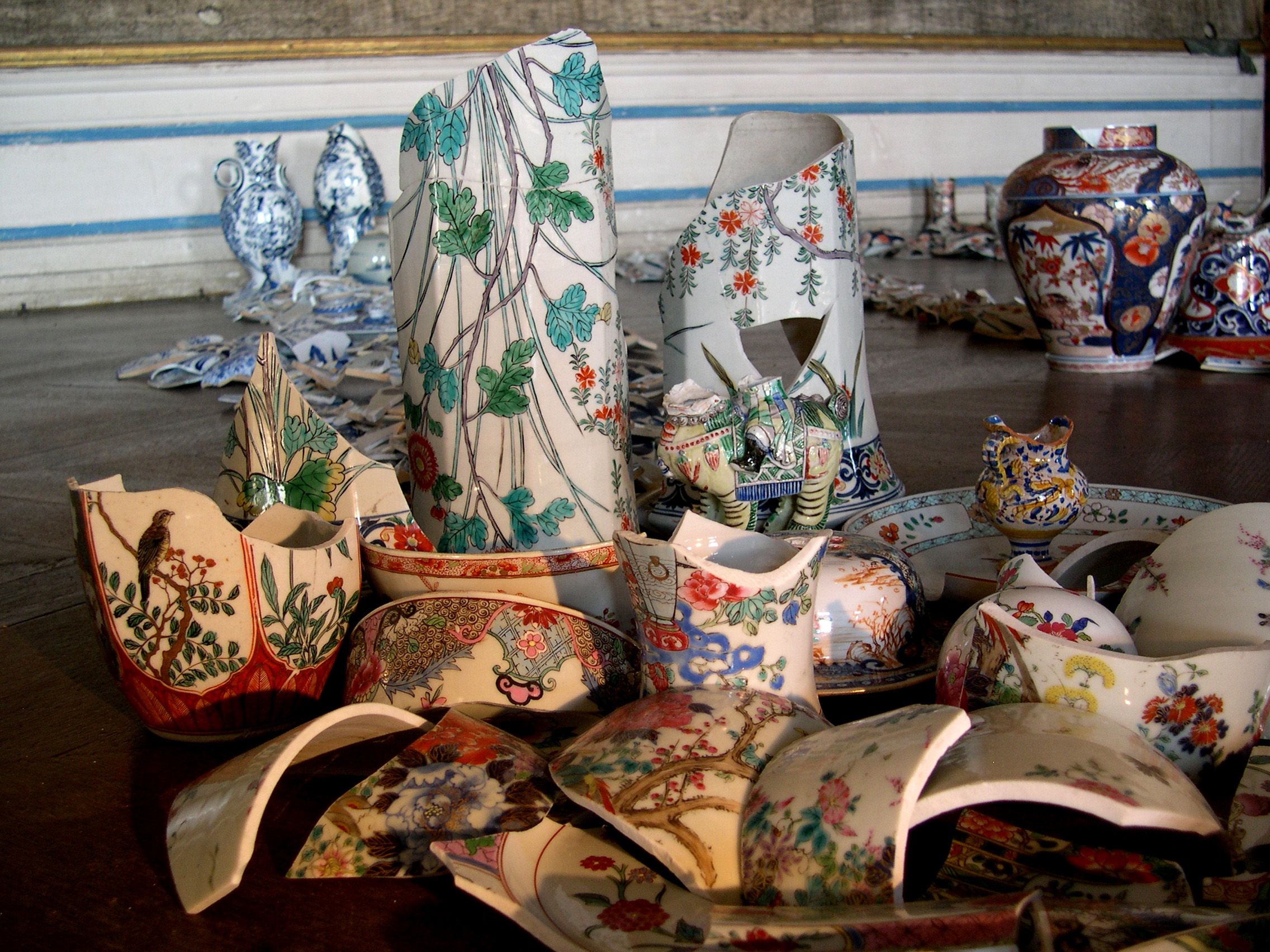 Törött porcelándarabok színes mintákkal a padlón.