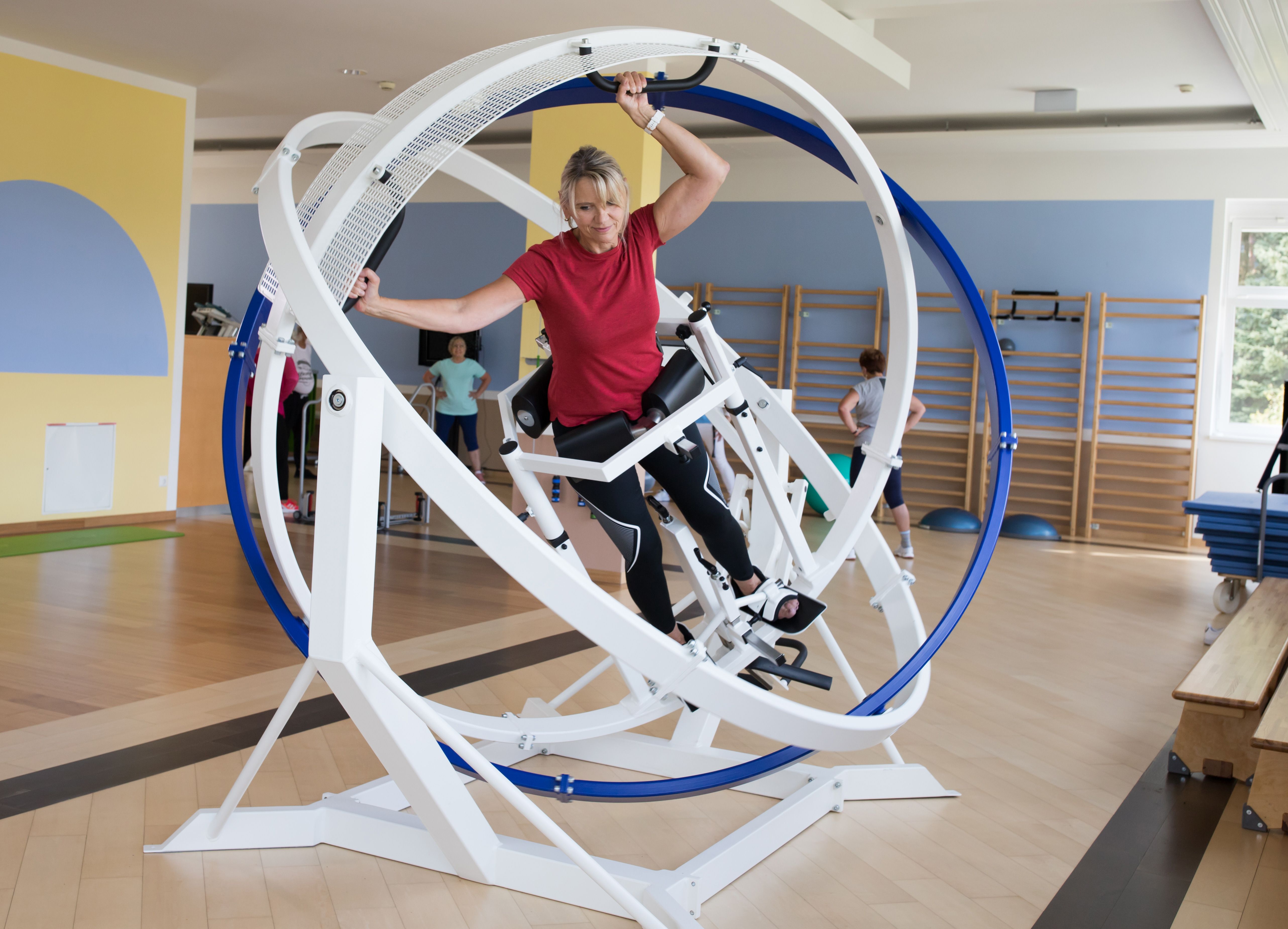 Egy nő tornázik egy forgó gyűrűkkel ellátott kondigépen egy fitneszközpontban.