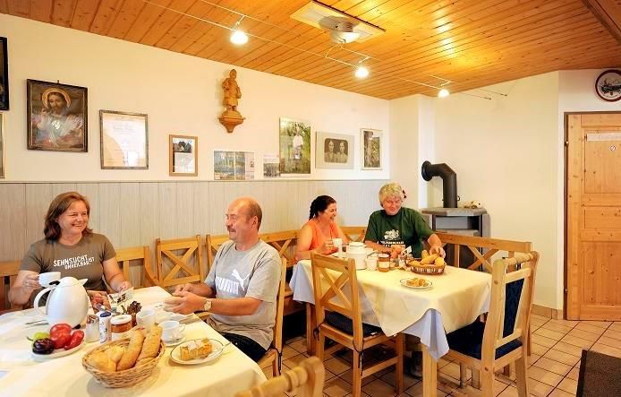 Az emberek egy hangulatos, fából készült bútorokkal és falidíszítéssel berendezett szobában reggeliznek.