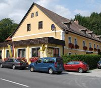 Egy sárga fogadó piros virágokkal és parkoló autókkal előtte.