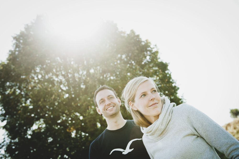 Egy férfi és egy nő áll odakint egy fa előtt, a nap átsüt a leveleken.