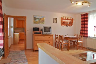 Hangulatos nappali fabútorokkal, étkezőasztallal, TV-vel és piros függönyökkel.