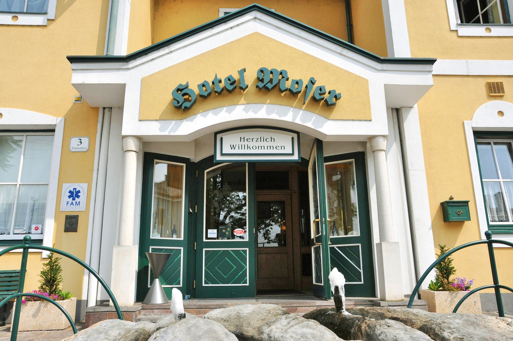 A Hotel Moser bejárata sárga homlokzattal és zöld ajtókkal.