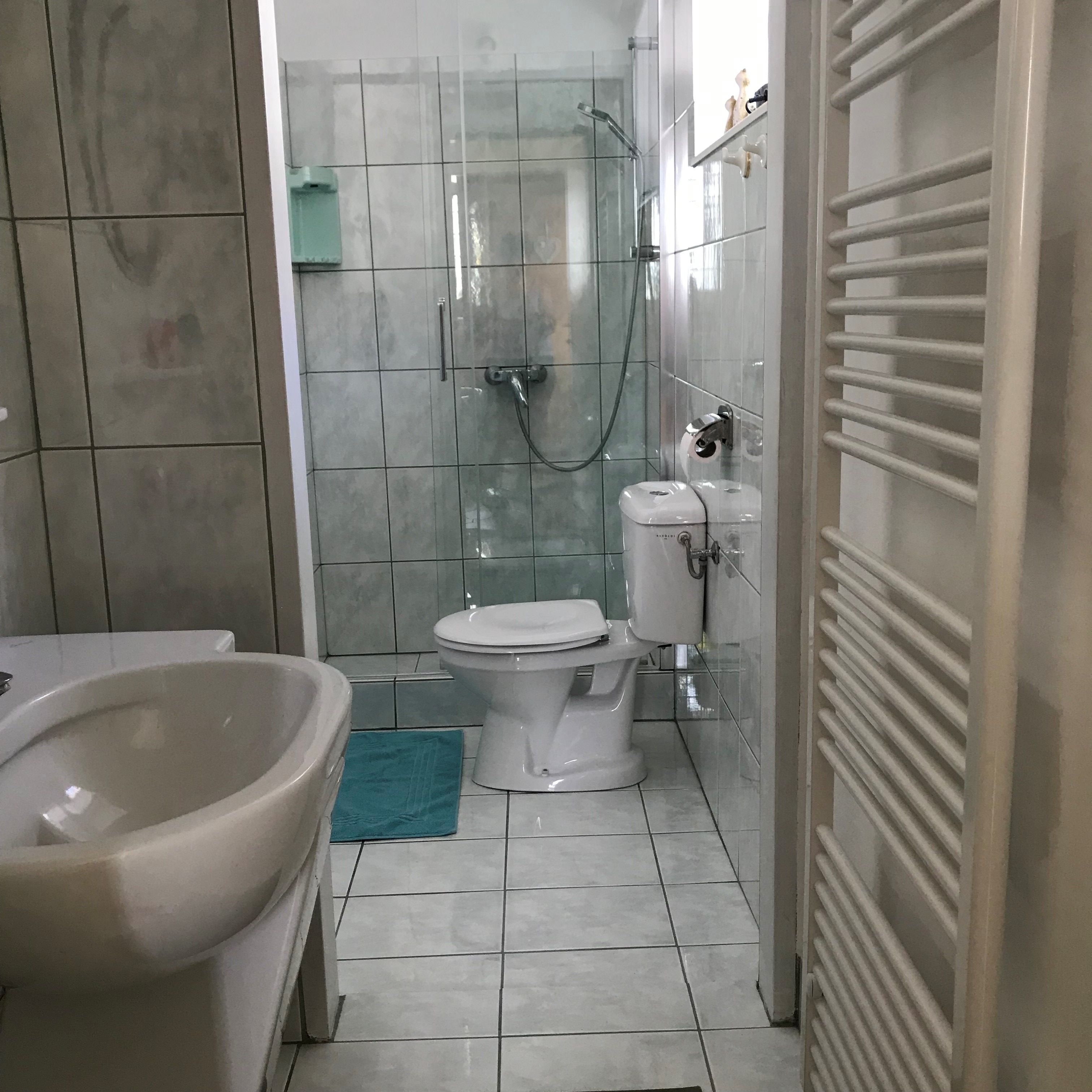 Modern fürdőszoba zuhanyzóval, WC-vel és mosdókagylóval.