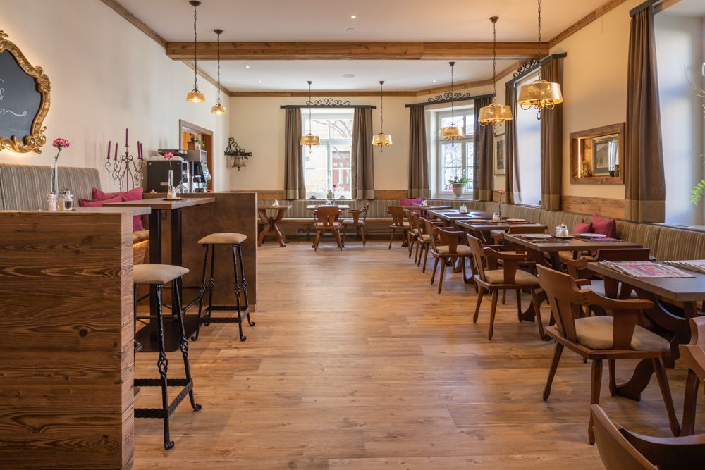 Hangulatos reggelizőhelyiség fabútorokkal és nagy ablakokkal.