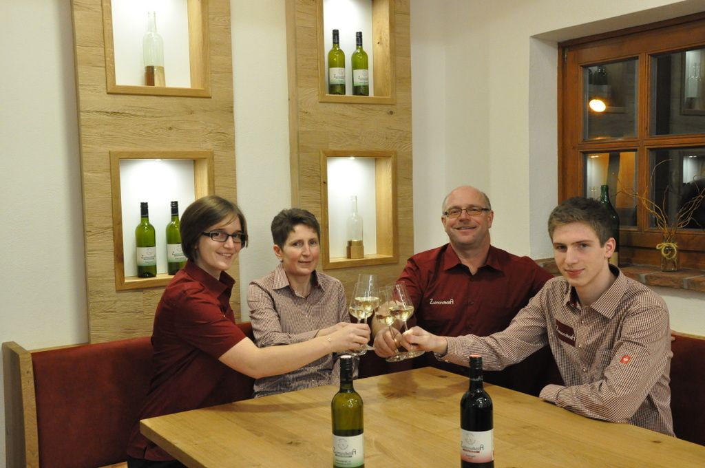 Négy ember koccint egy asztalnál a borospoharakkal.