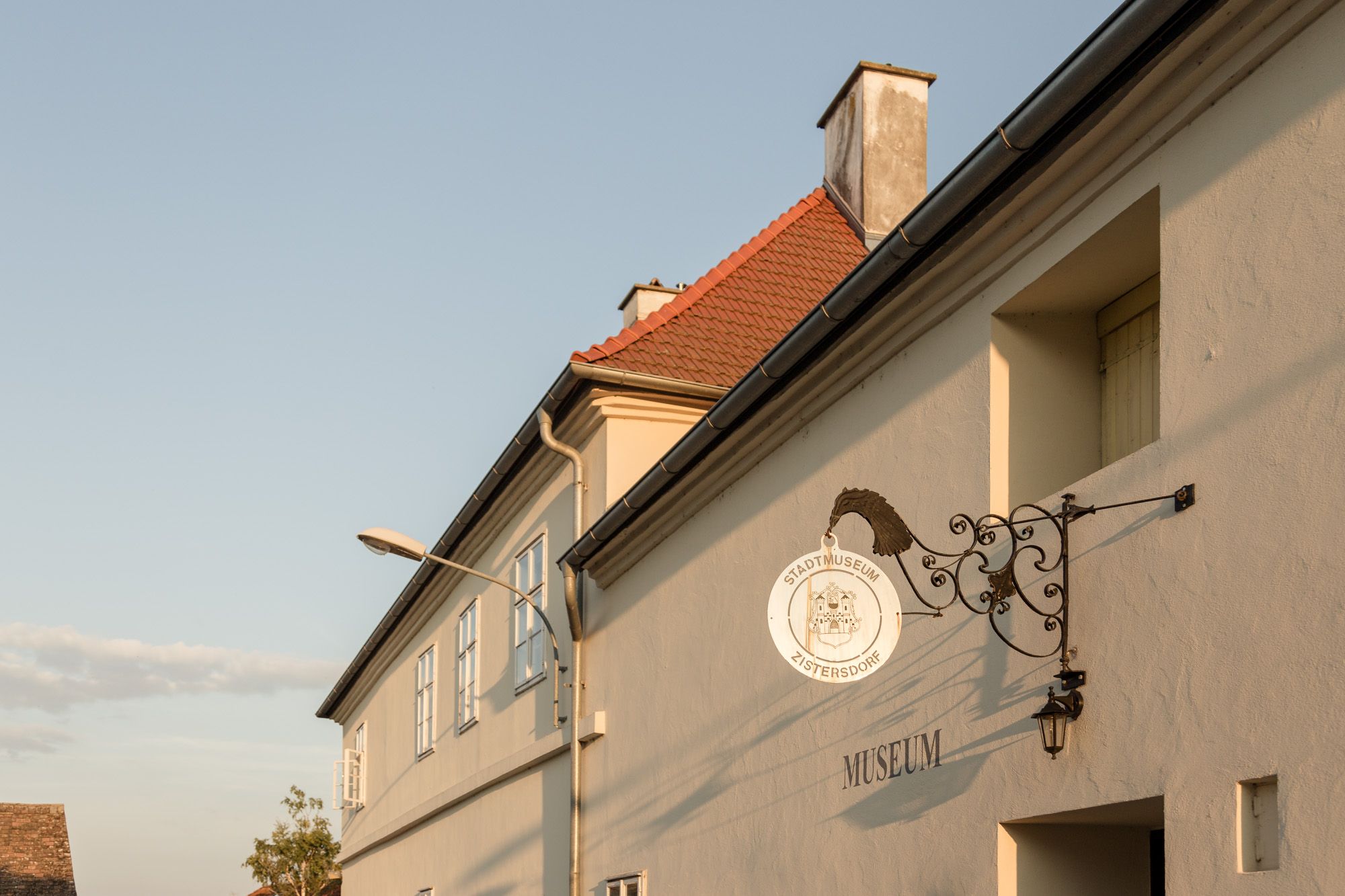 A zistersdorfi városi múzeum külső nézete, előtérben egy díszes felirat és egy lámpaoszlop.