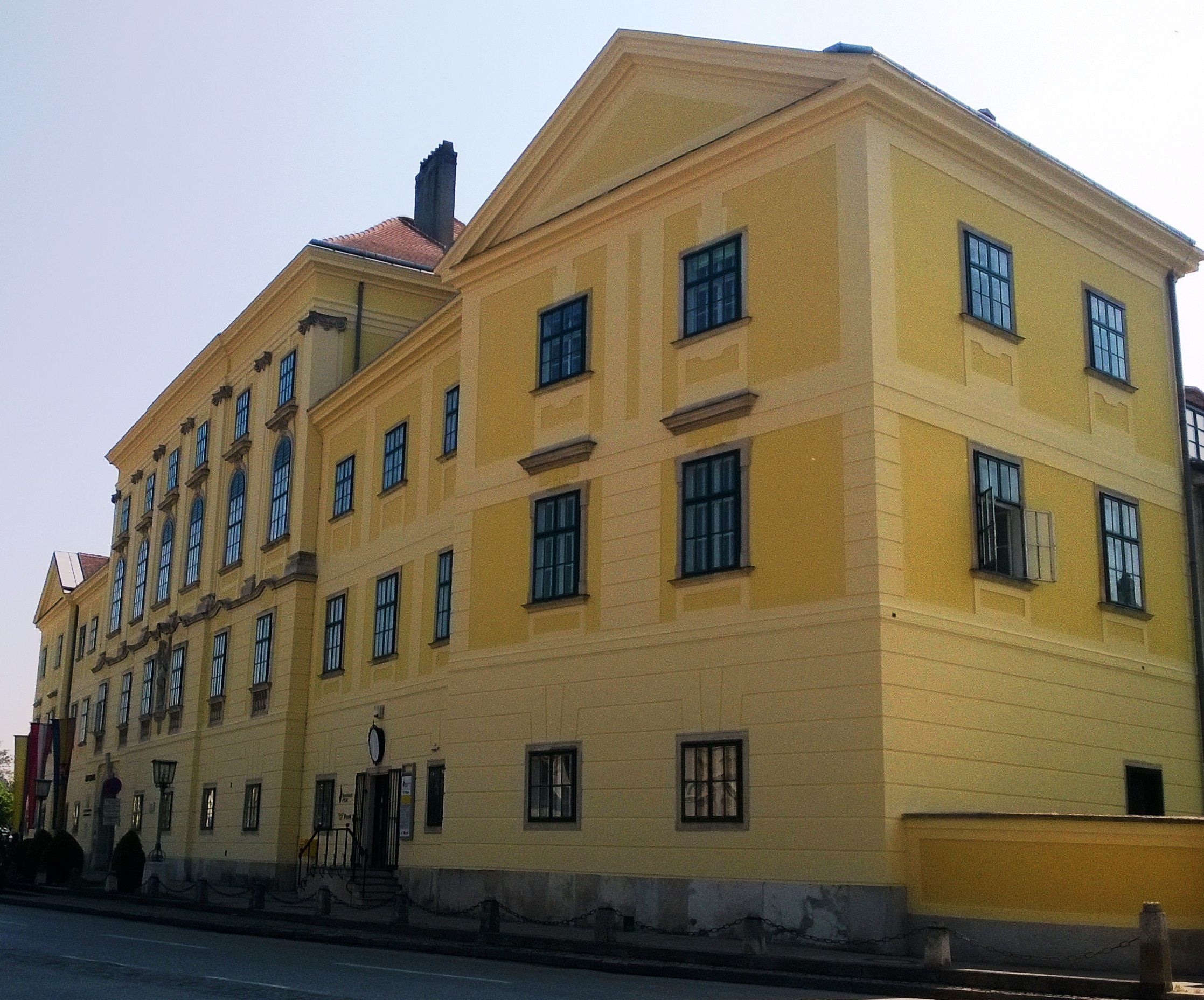 Sárga színű történelmi épület sok ablakkal és nyeregtetővel.