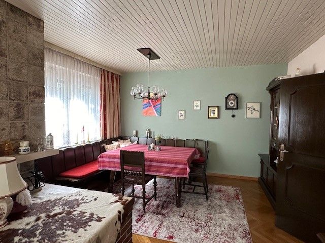 Hangulatos nappali étkezőasztallal, sarokpaddal, szőnyeggel és faliórával.