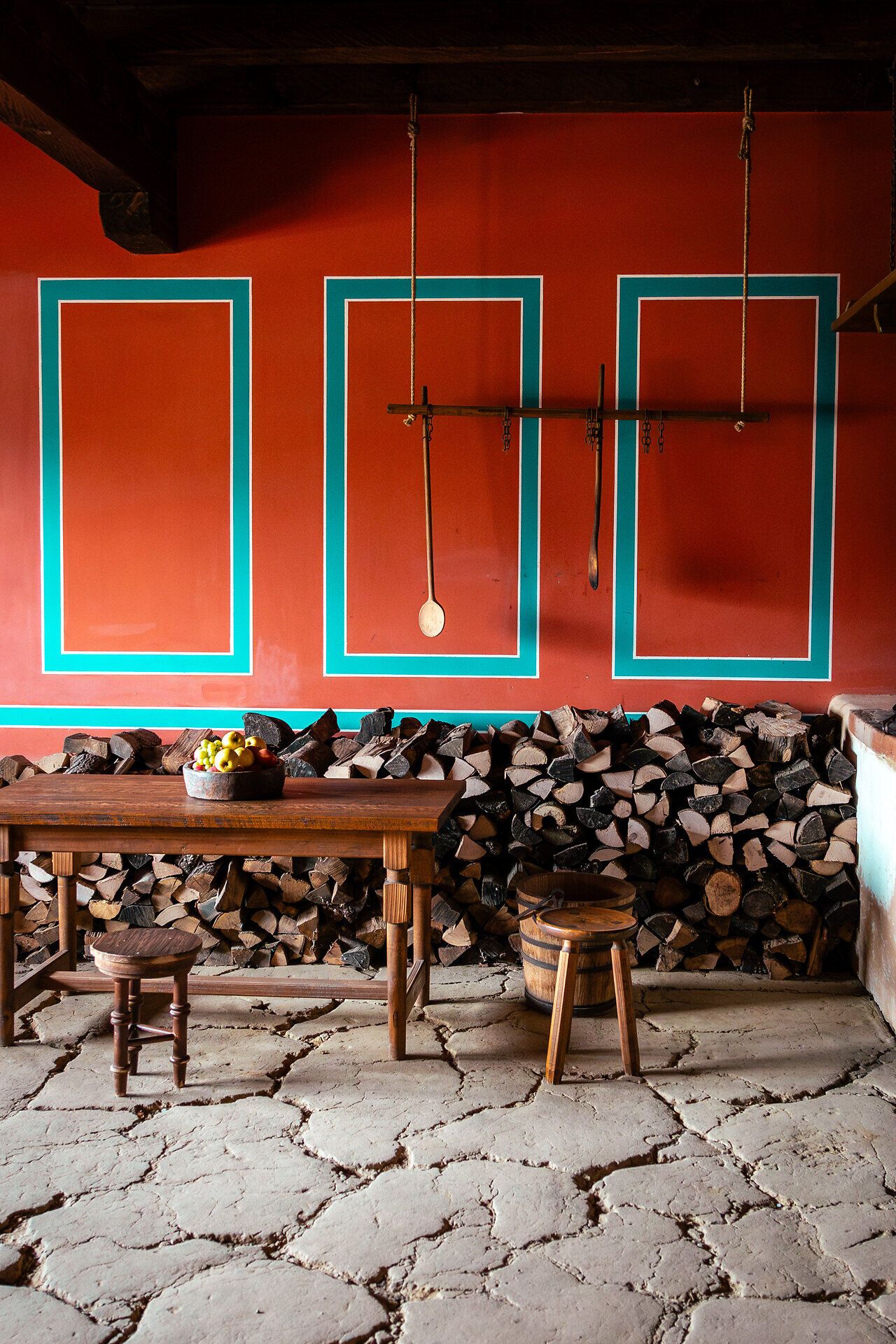 Innenaufnahme eines römischen Hauses mit roter Wand, Holztisch und Holzsessel.