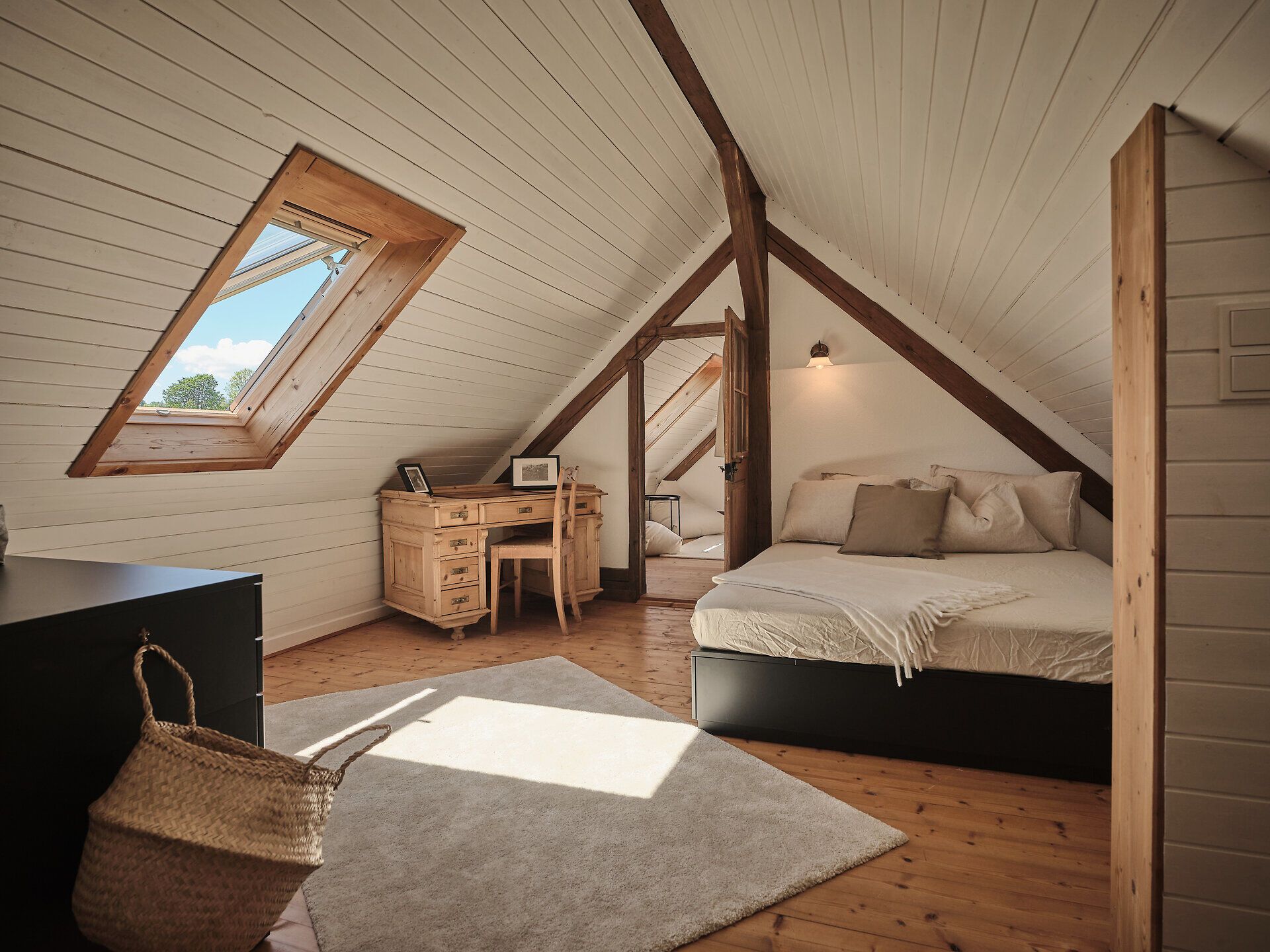 Rusztikus kőház faajtóval, paddal és virágokkal az előtérben.