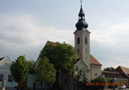 Moosbrunni templom zöld templomtoronnyal és a környező épületekkel.