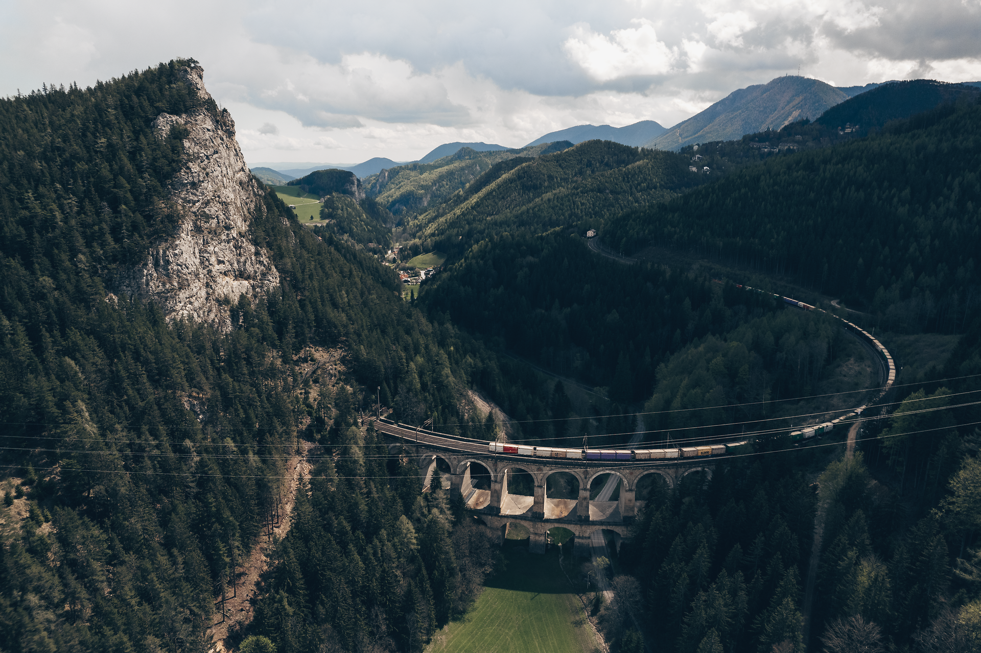 Umgeben von majestätischen Bergen und dichten Wäldern schlängelt sich die Semmeringeisenbahn elegant durch die Landschaft. Die beeindruckende Brücke, die über das grüne Tal führt, bietet atemberaubende Ausblicke und lädt zu unvergesslichen Erlebnissen in der Natur ein.