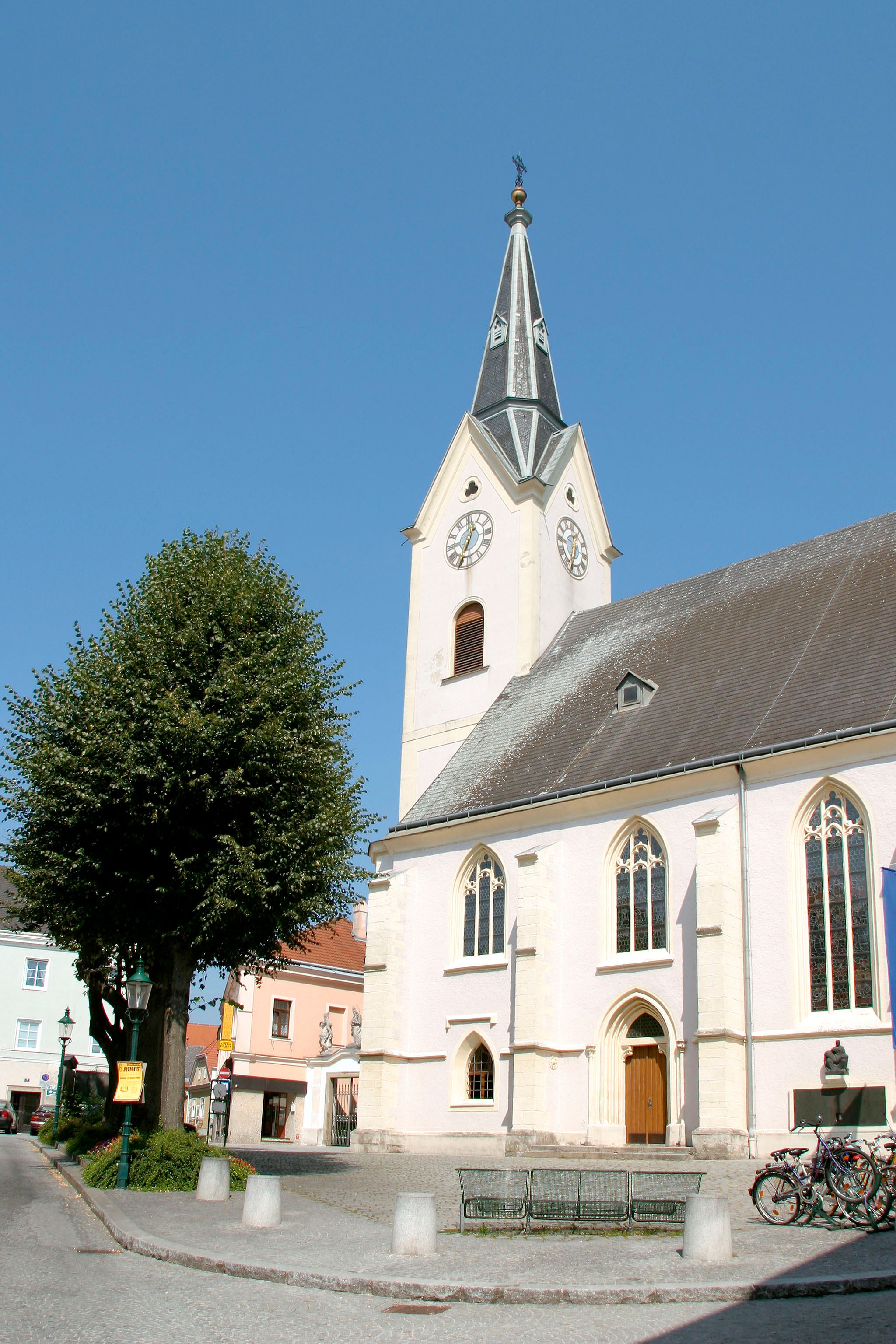 Szent Lőrinc plébániatemplom toronnyal és órával a kék égbolton.