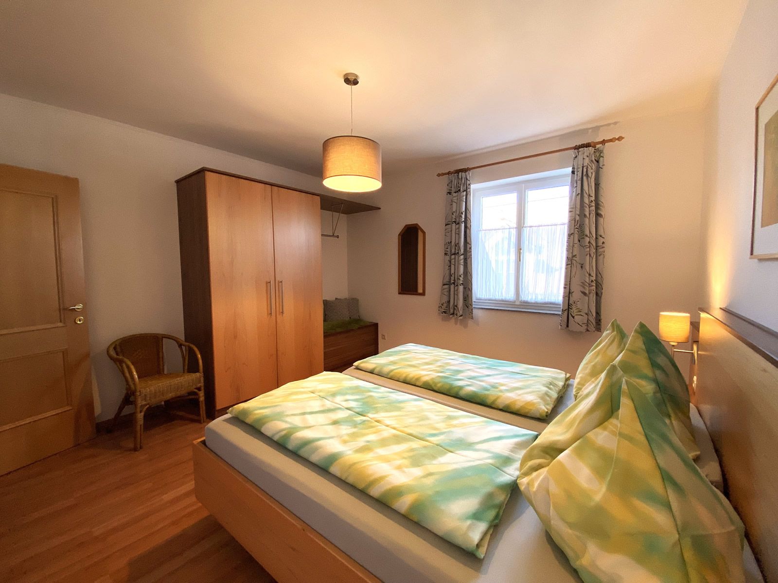 Hálószoba franciaággyal, szekrénnyel, székkel és ablakkal.