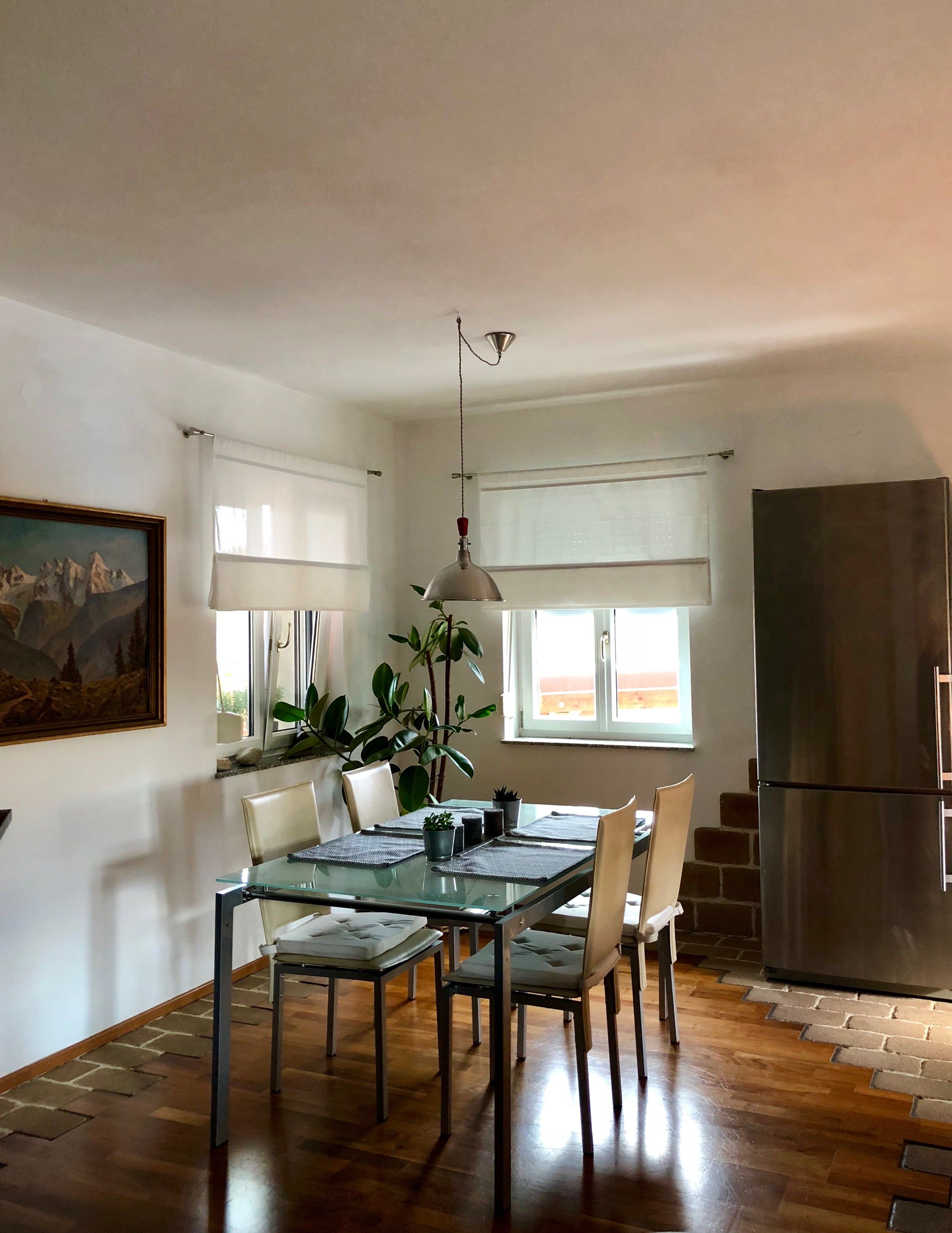 Nyitott nappali és étkező asztalokkal, székekkel és természetes fénnyel.