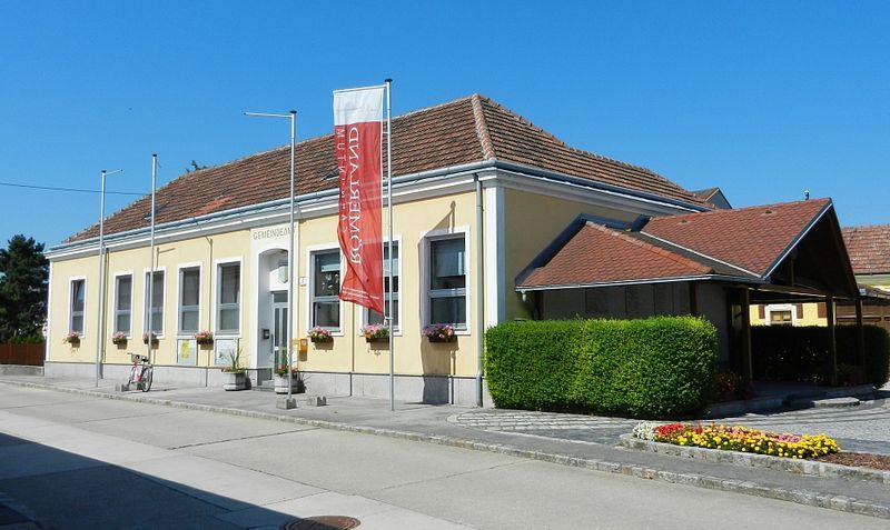 Városi hivatal Rauchenwarthban, sárga épület piros tetővel és virágokkal.