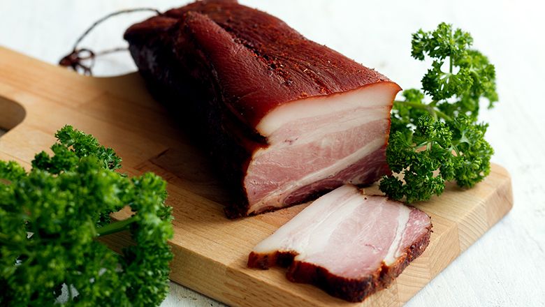 Egy szelet szalonna fadeszkán petrezselyemmel.