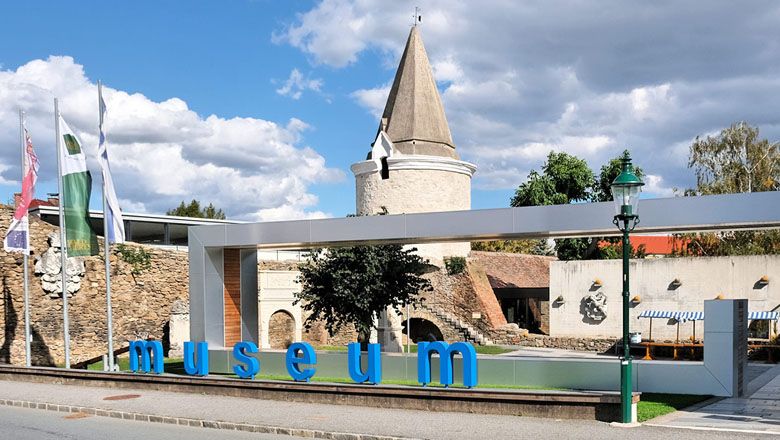 A Horn Múzeum bejárata modern felirattal és történelmi toronnyal a háttérben.